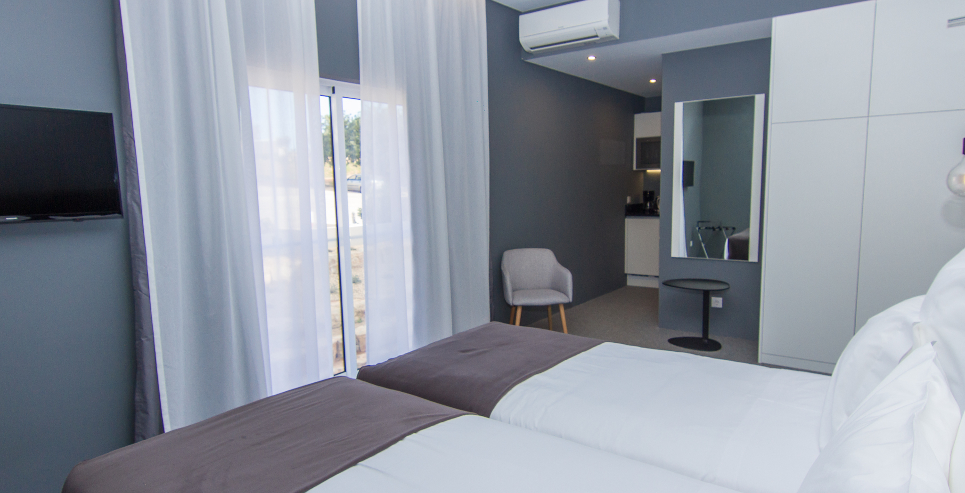 The Classic room at Pestana Gramacho Residences has two single beds, air conditioning, a window, and a mirror