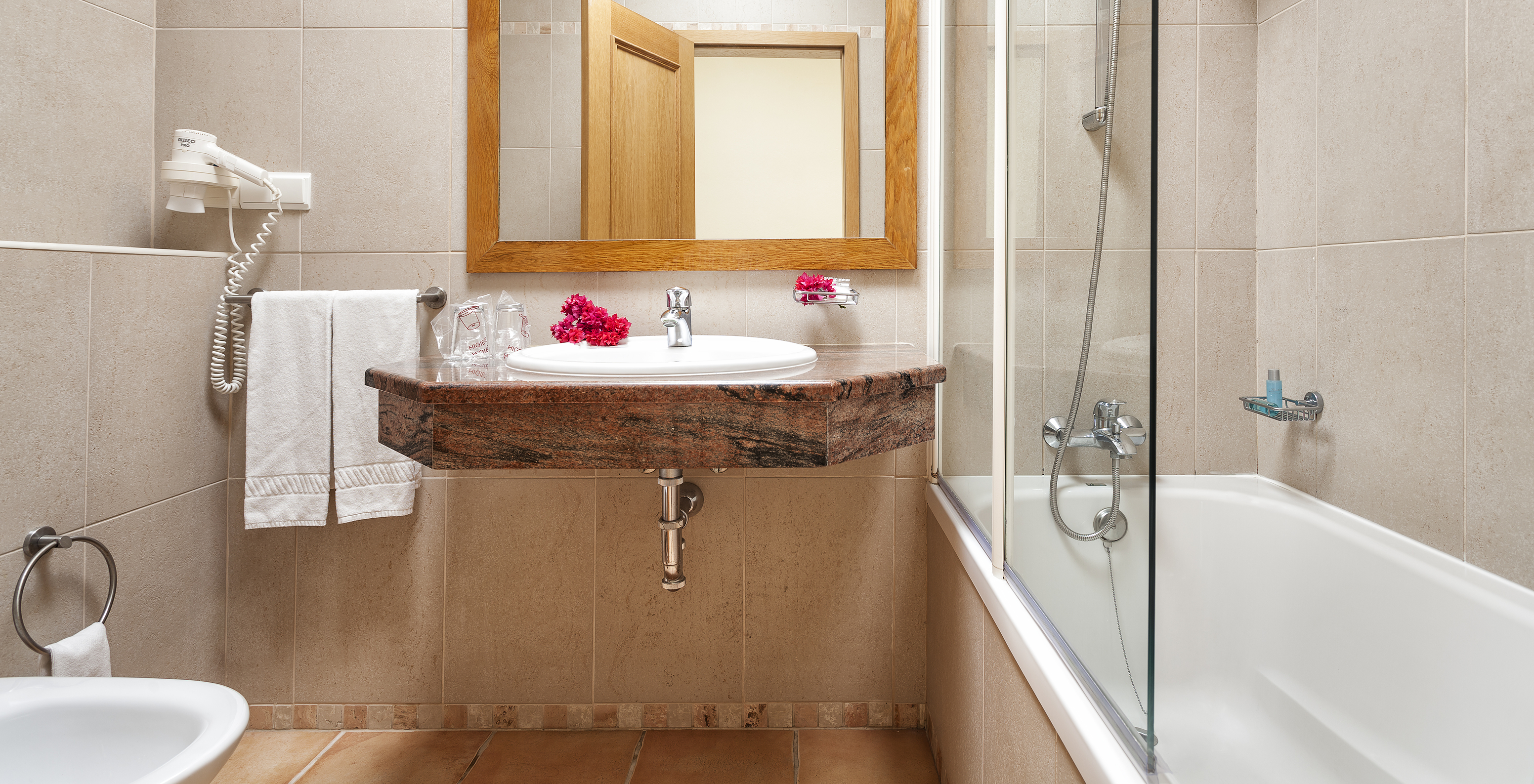 The T1 Apartment Land do Pestana Palm Gardens has a bathtub with shower, a sink with flowers and a mirror