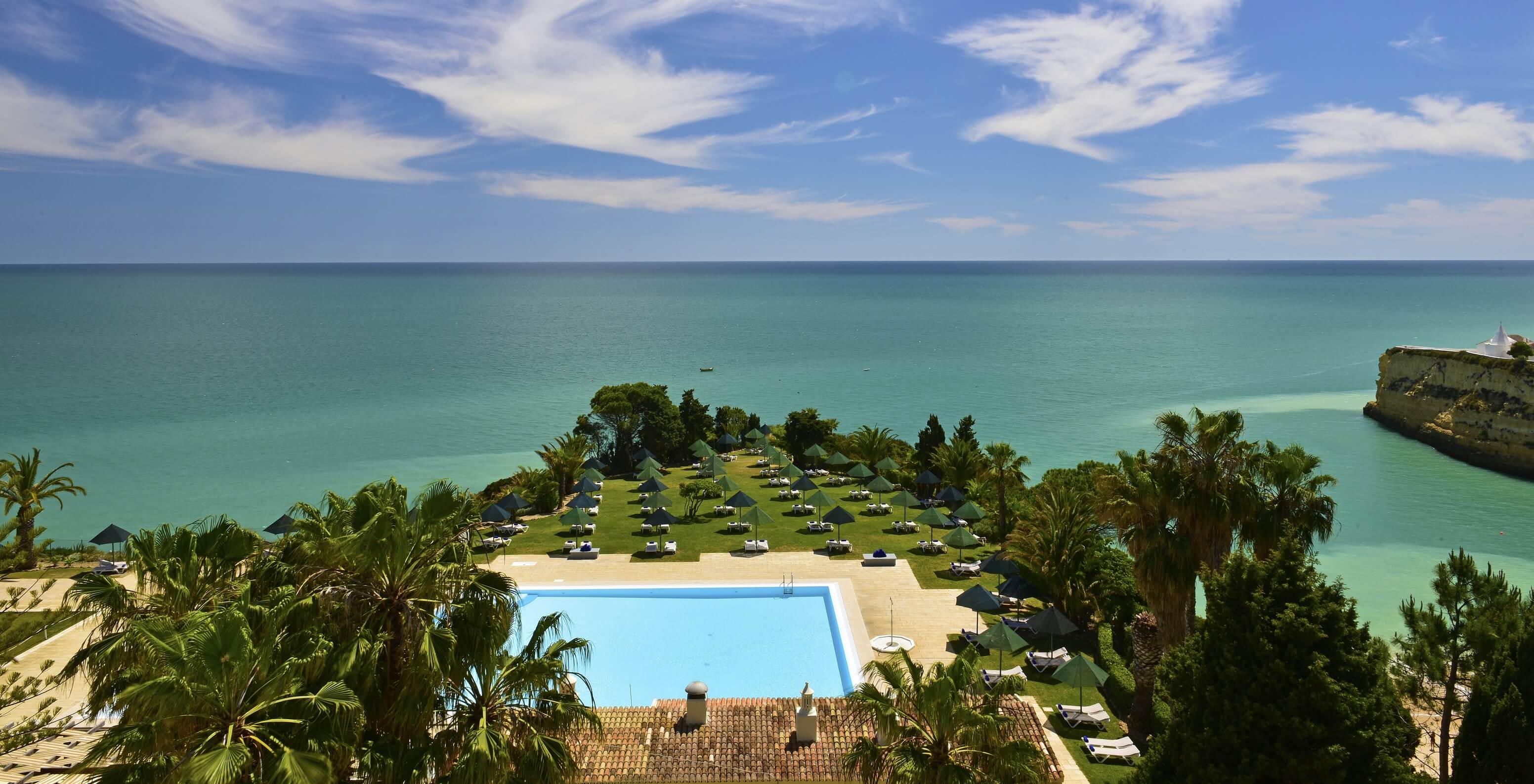 View of the outdoor pool at Pestana Viking, facing the sea and surrounded by palm trees