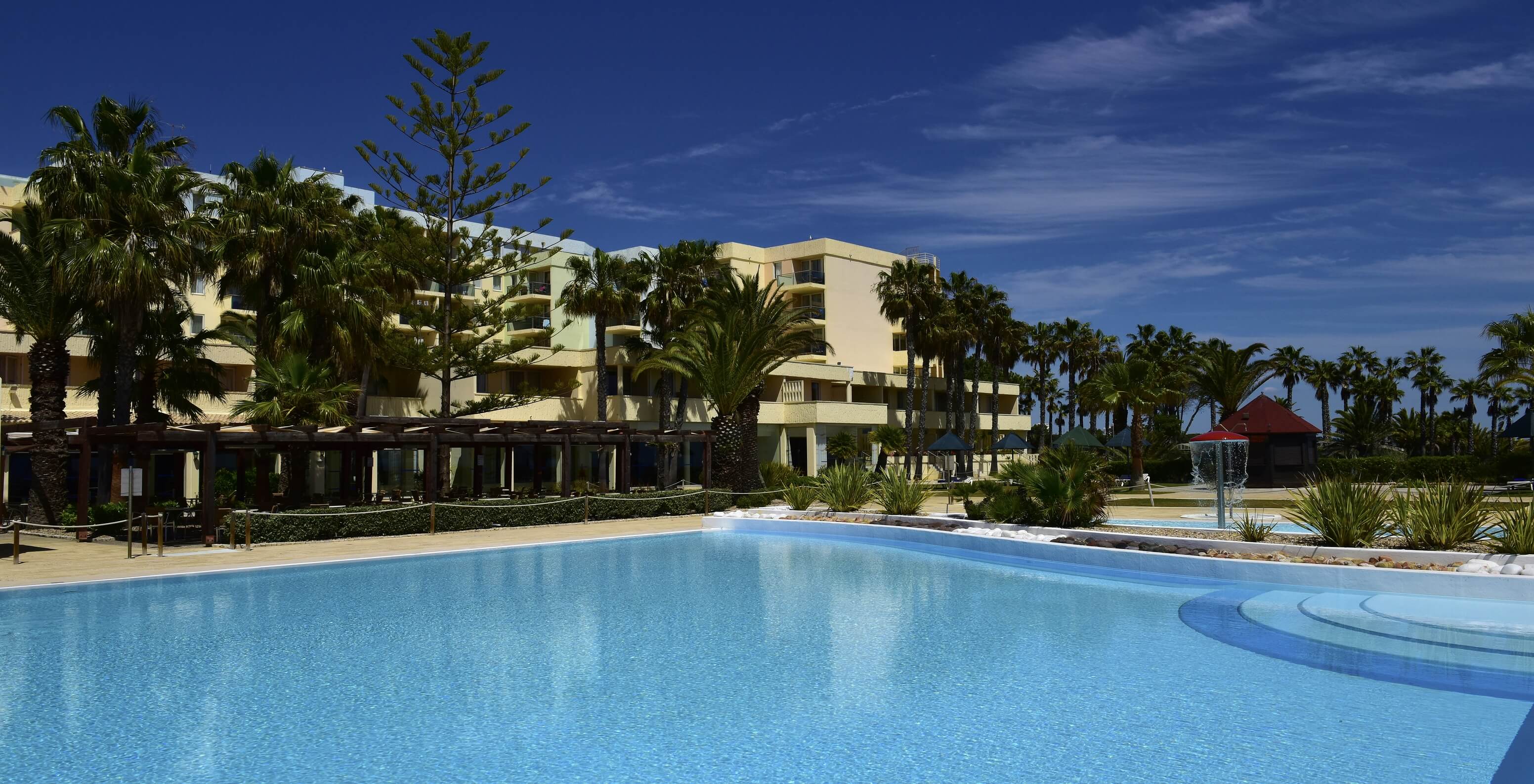 Outdoor pool at Pestana Viking, surrounded by palm trees and a bar for light meals