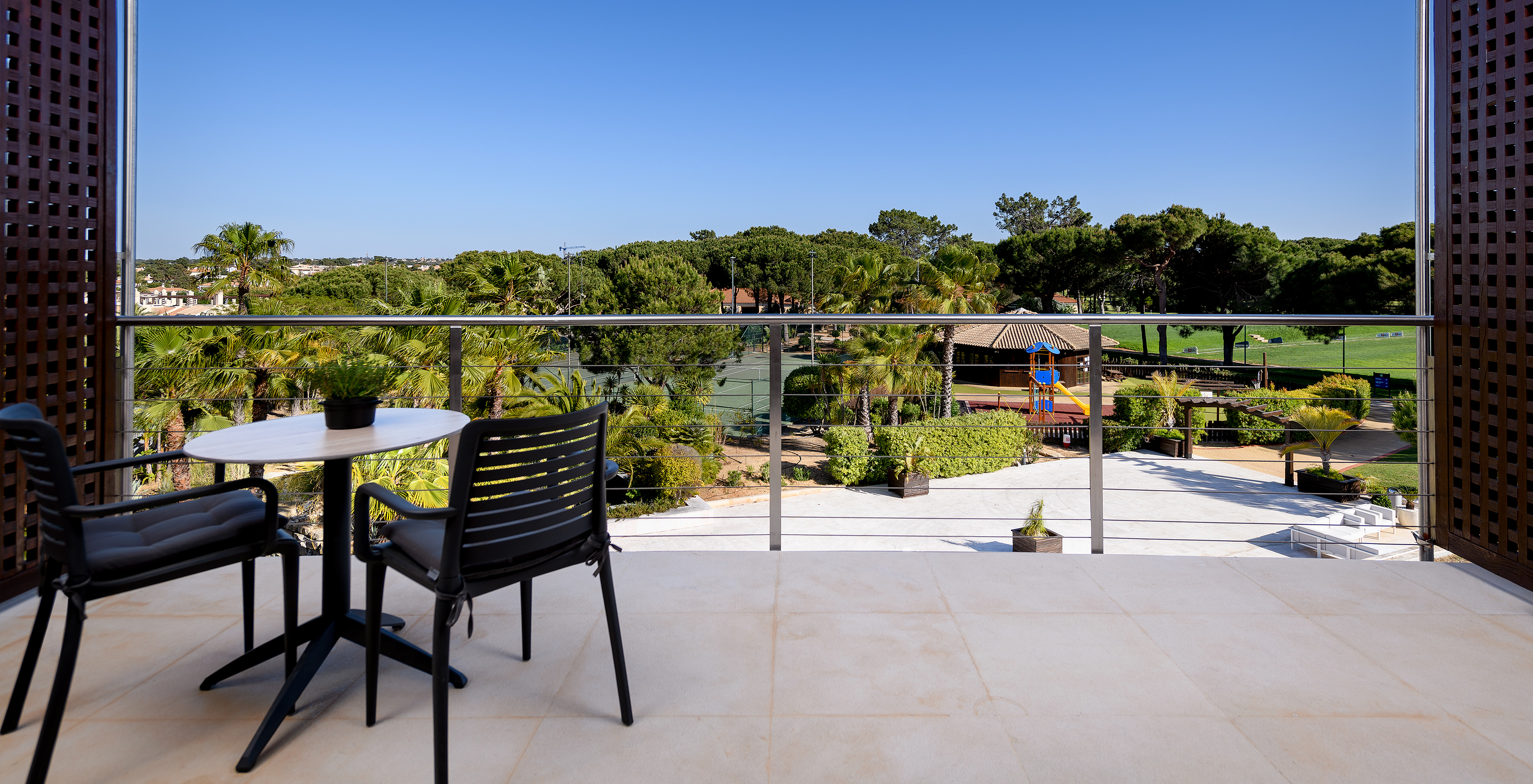 The Deluxe Golf room at Pestana Vila Sol - Vilamoura has a balcony with a table and chairs, and view of a golf course