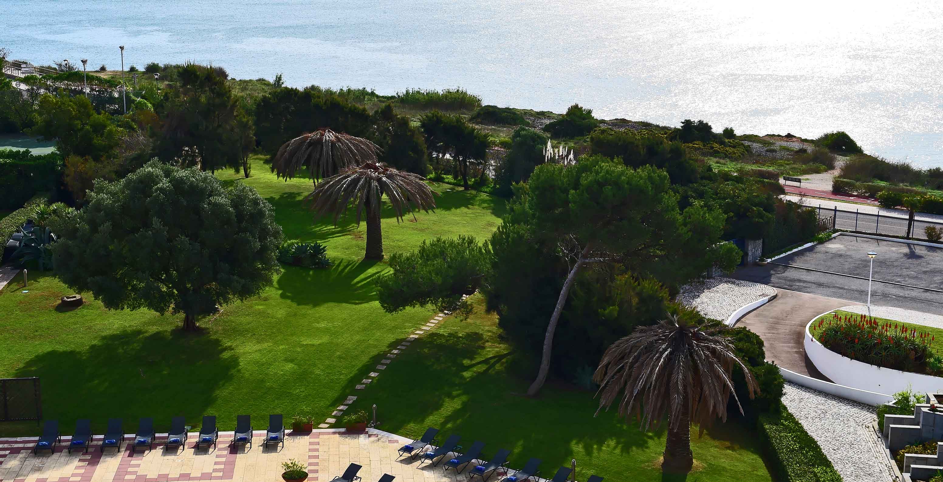 View from the hotel room of Pestana Cascais, where you can see the sea and the hotel's garden with some sun loungers.