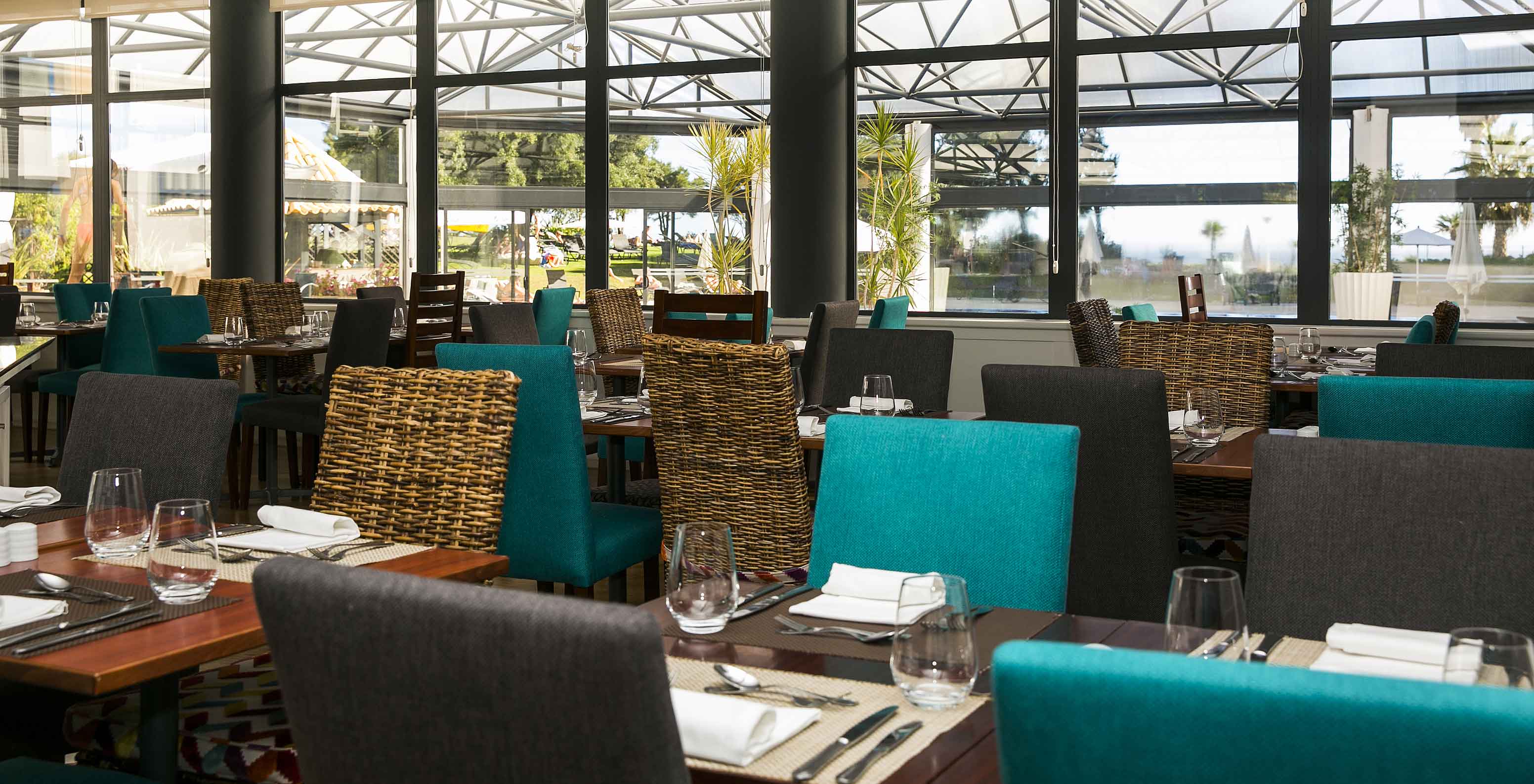 The Oceano restaurant, at the 4-Star Hotel in Cascais, has wooden tables with placemats and blue, gray, and straw chairs.