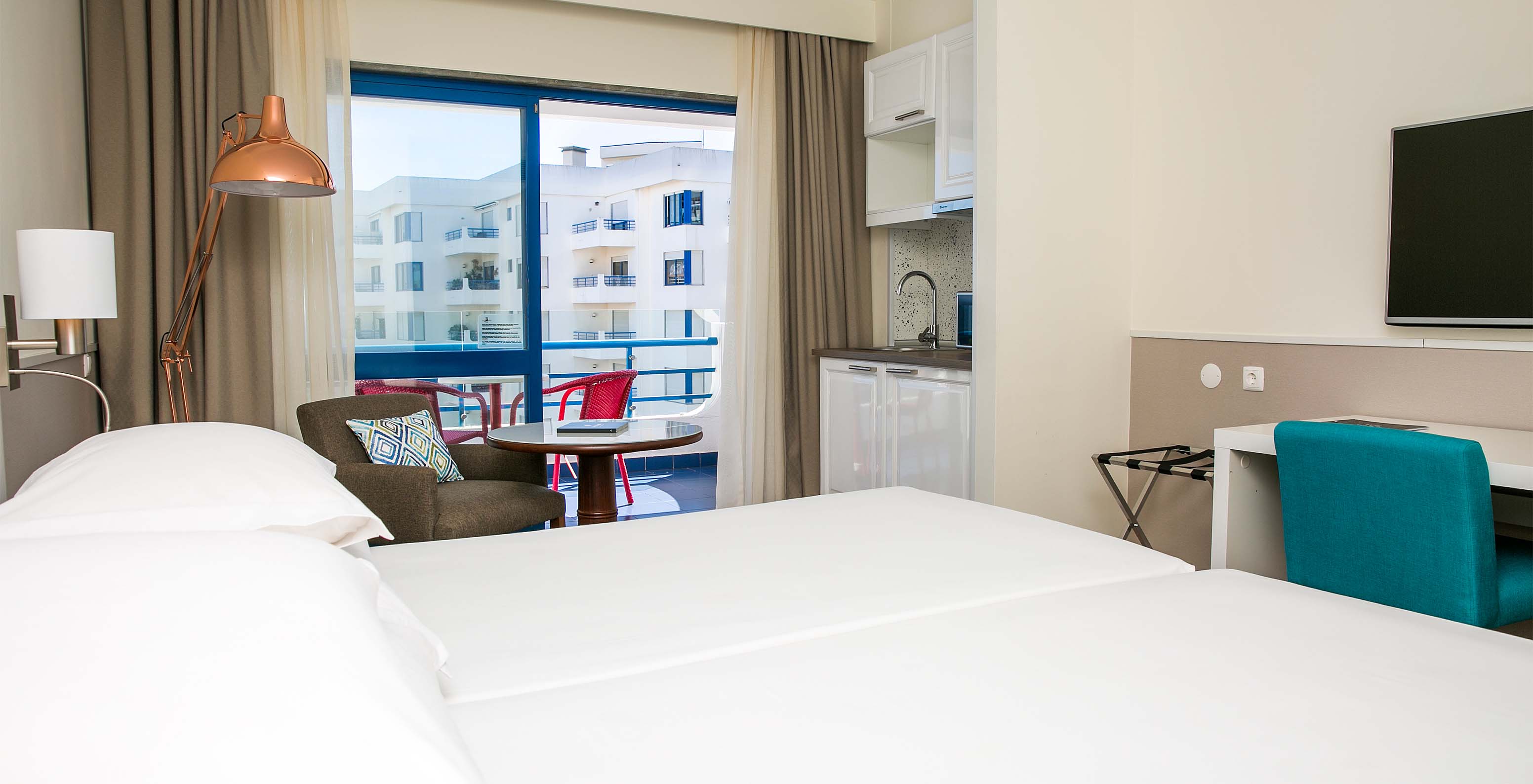 The Superior Deluxe room at Pestana Cascais has two single beds, a TV, and a balcony with chairs and tables