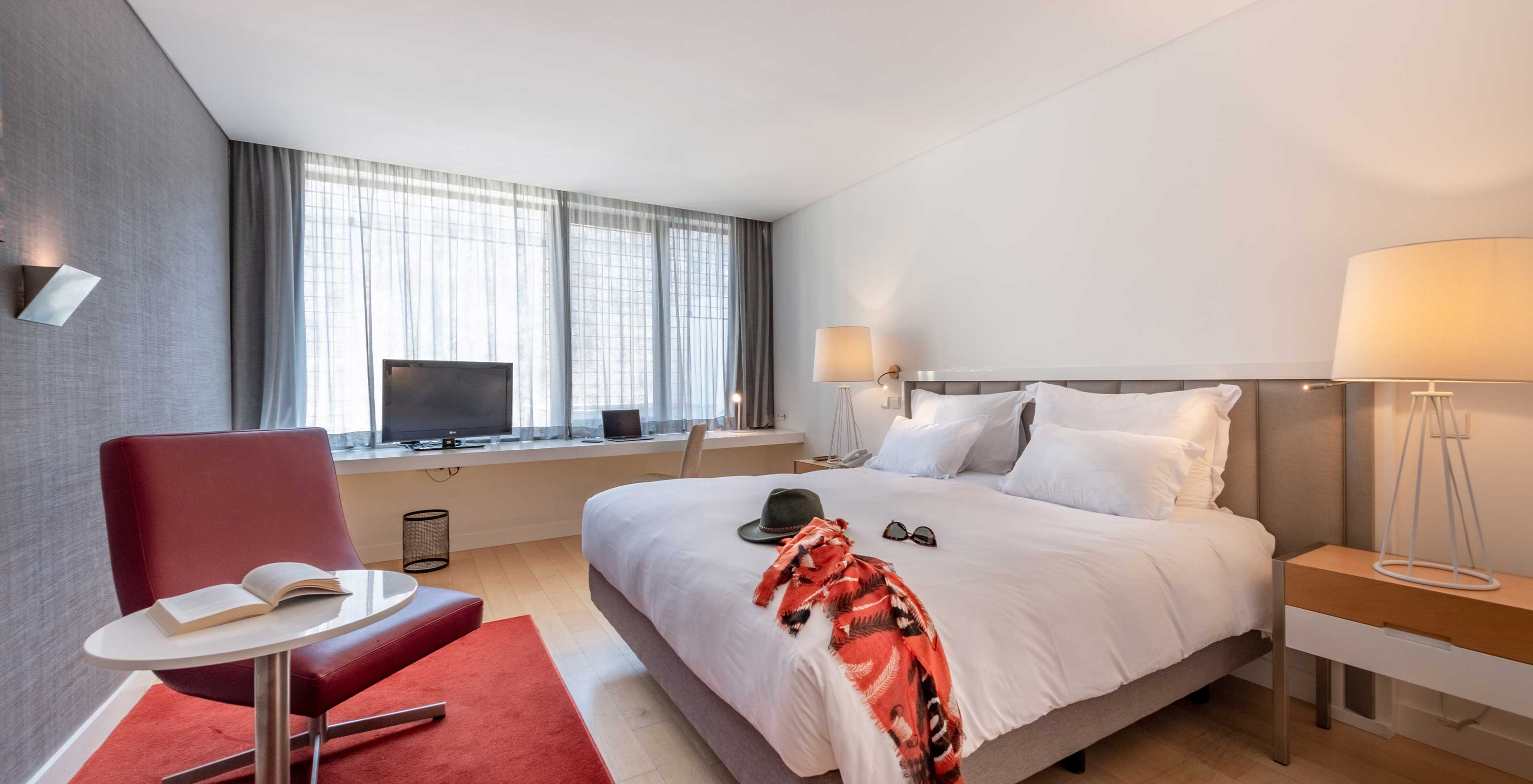 The Classic Room at Pestana Cidadela Cascais has a double bed, a TV, a red carpet, and a large window