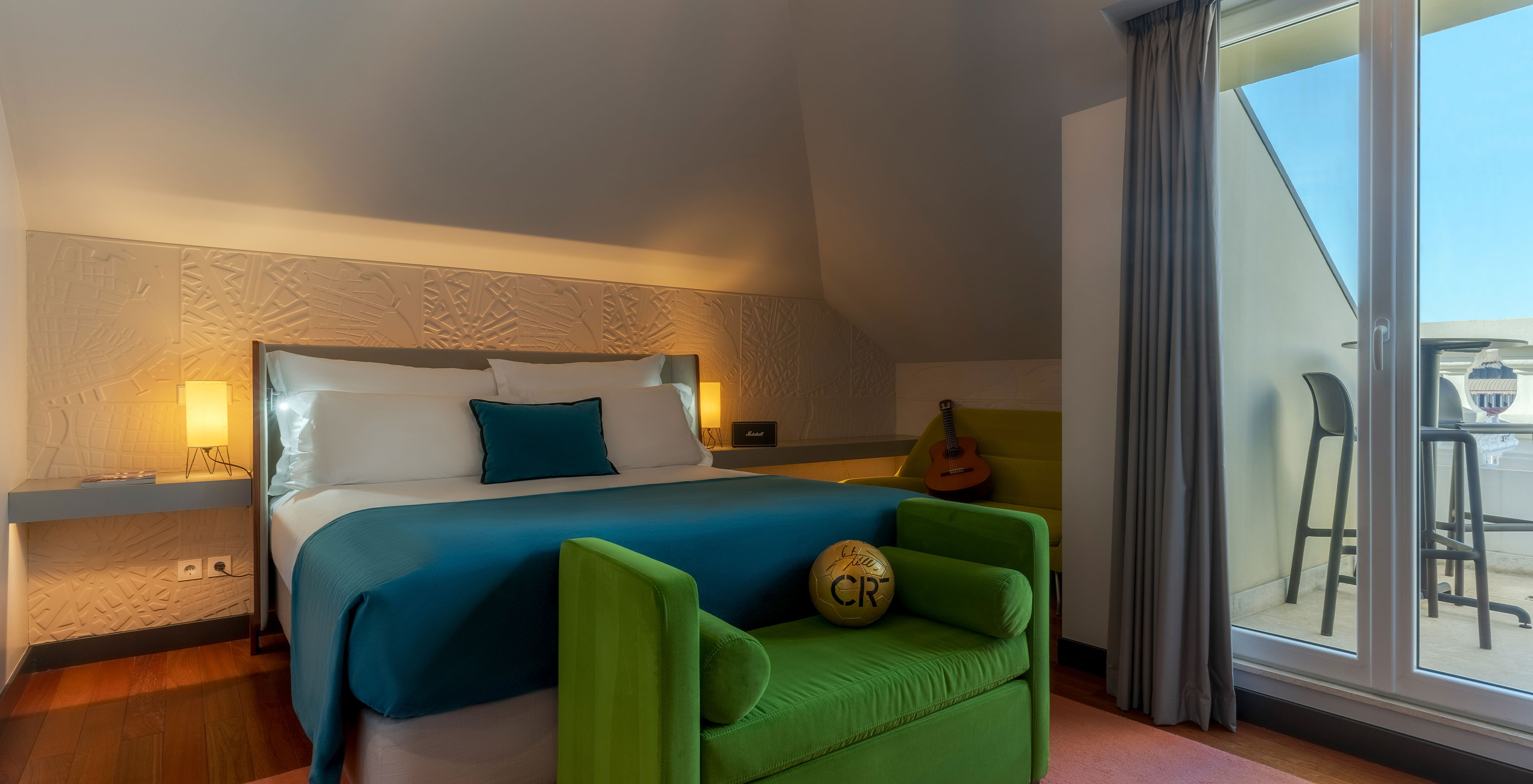 The CR7 Suite at Pestana CR7 Lisboa features a double bed, a bench at the foot, and a signed football