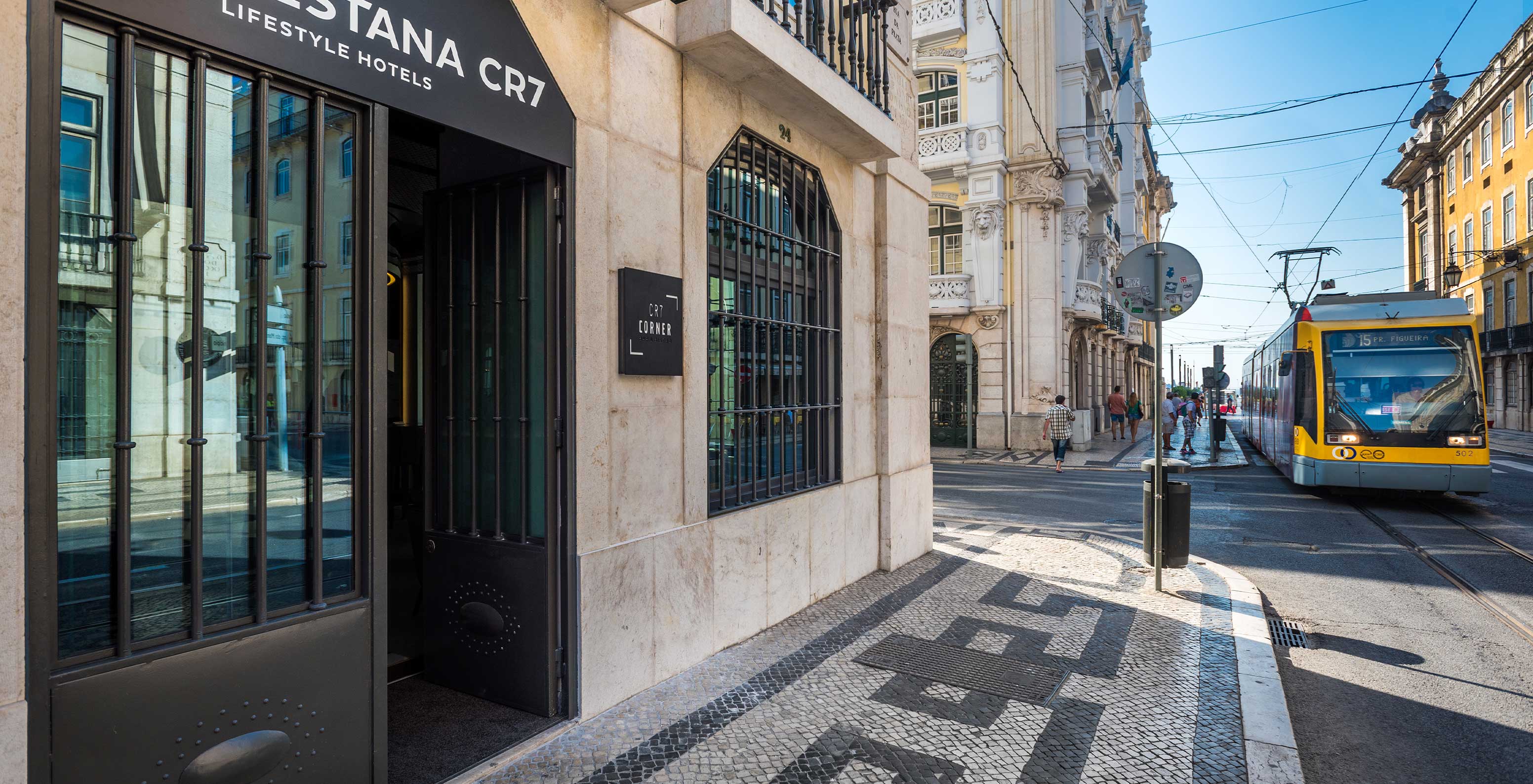 Hotel exterior with Portuguese pavement on the sidewalk with a tram passing by