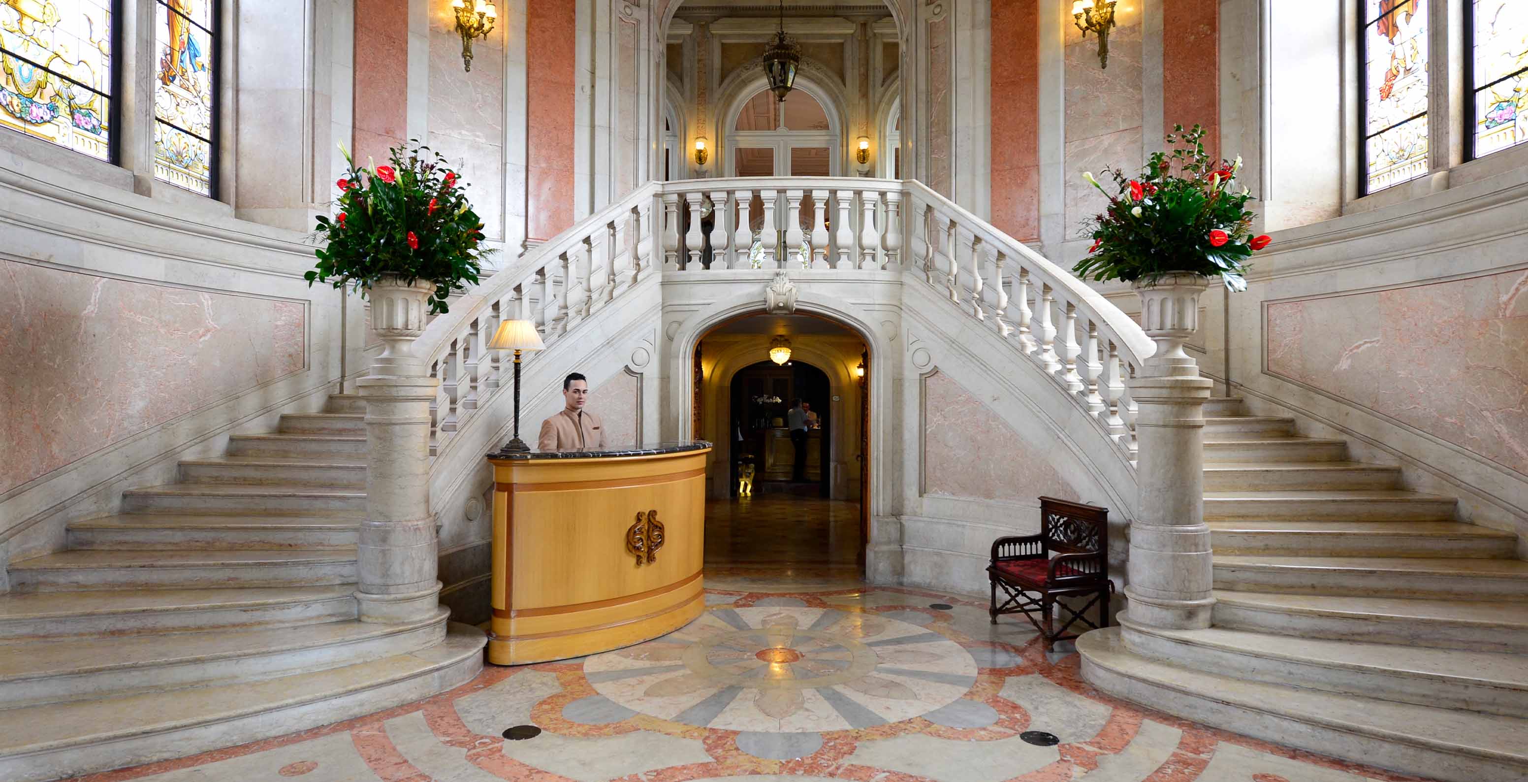 Reception, staff member, and white marble spiral staircase at Palace Lisboa, a hotel in a palace in Lisbon