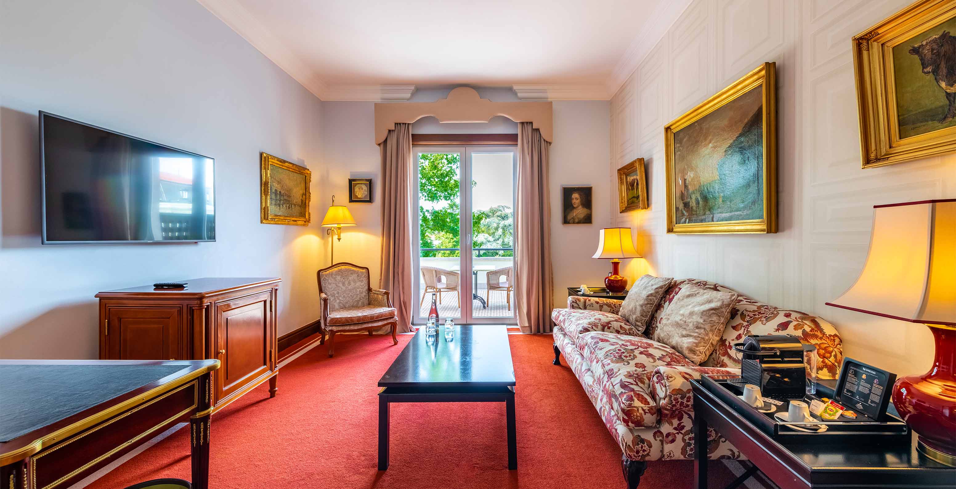 The Suite Collection at Pestana Palace Lisbon has a living room with a sofa, television and a window to access to the balcony