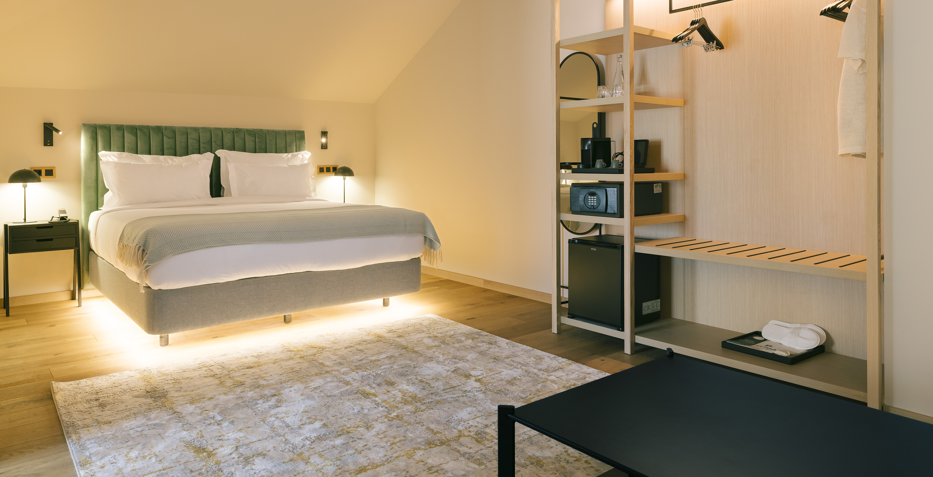 The Junior Suite of Pestana Rua Augusta Lisboa has an illuminated double bed and an open wardrobe with hangers and shelves