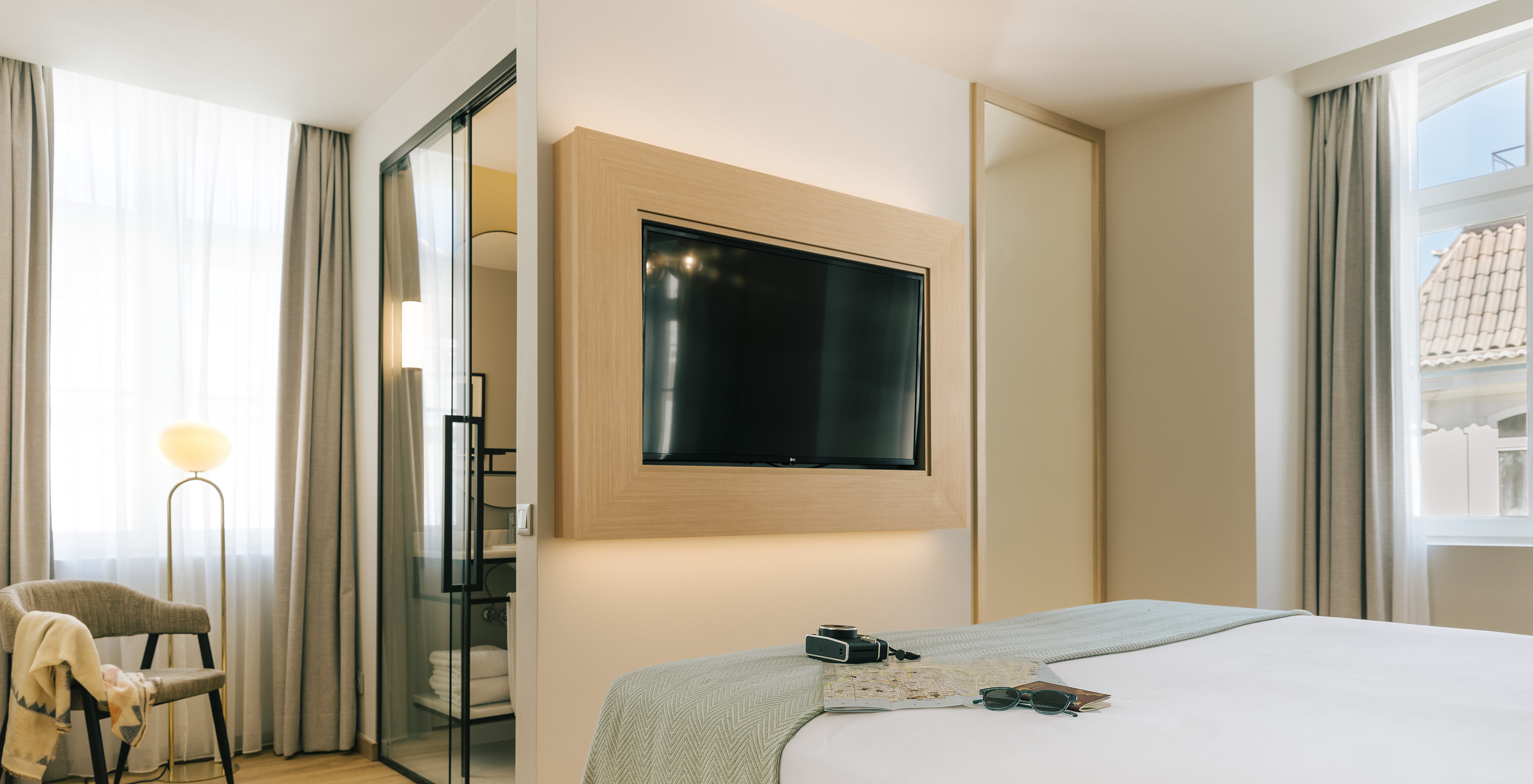 The Premium Corner of Pestana Rua Augusta Lisboa has a bed with television in front and a bathroom with glass door