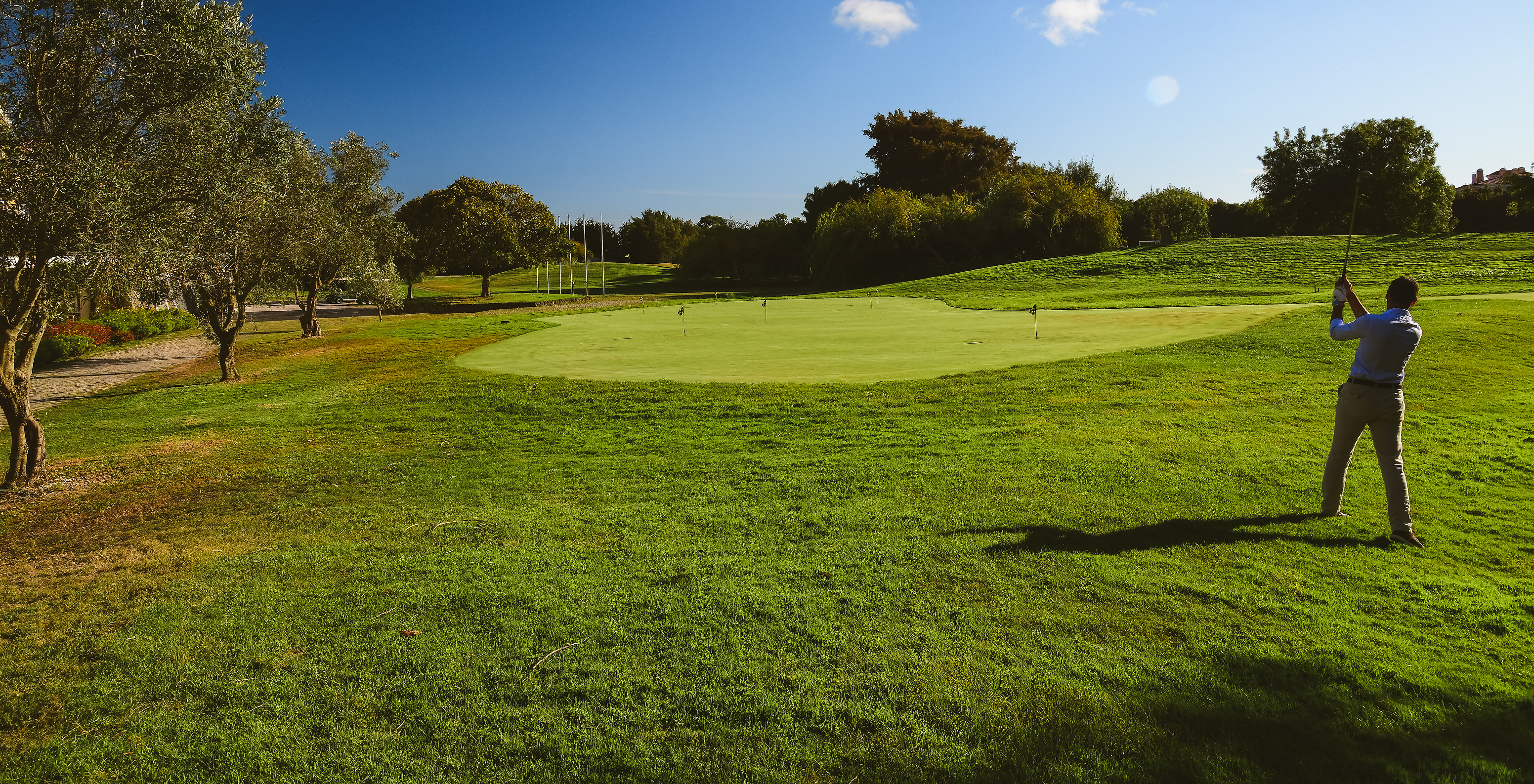 Man making a shot on the golf course on a sunny day with a blue sky at Pestana Sintra Golf