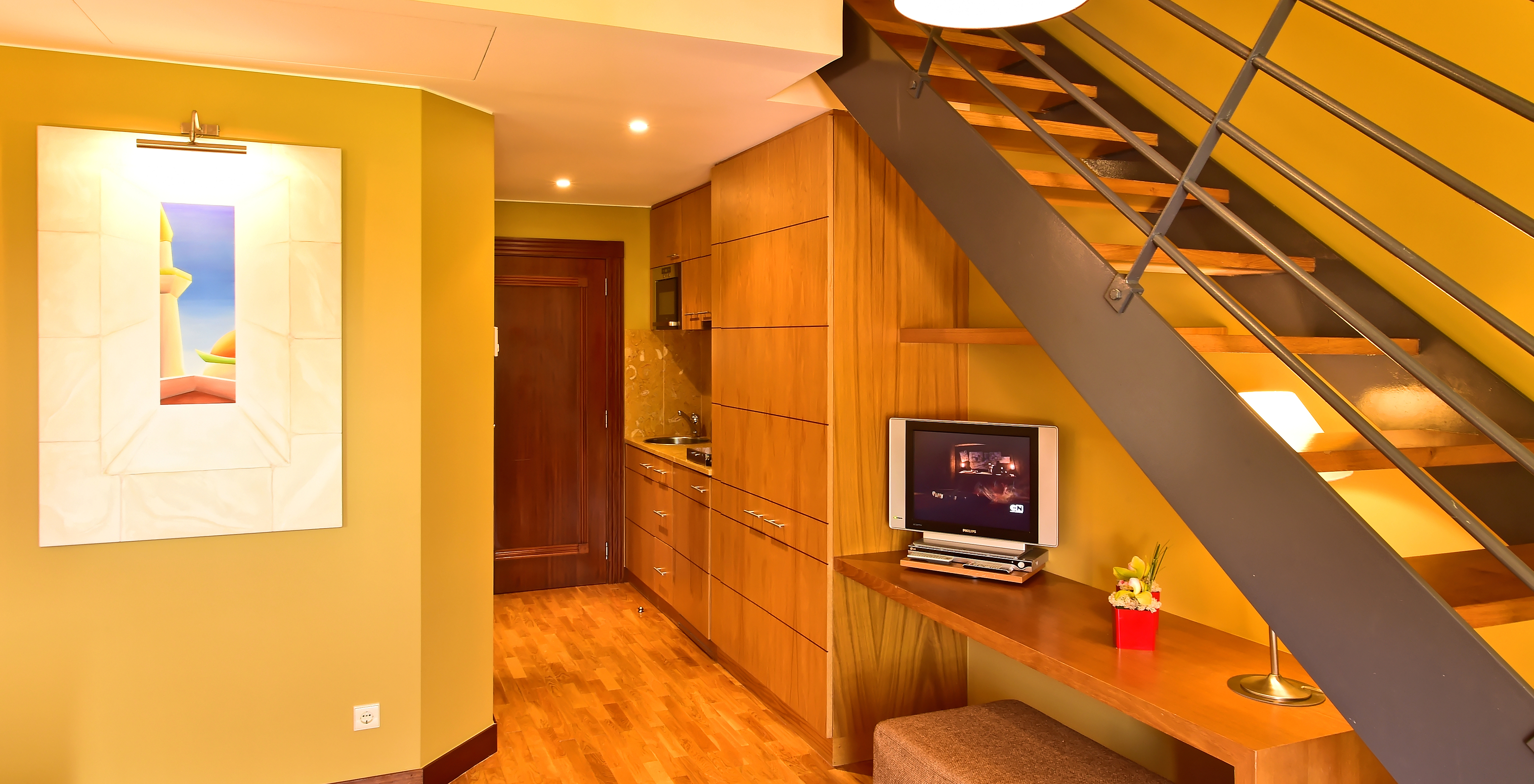 The Mezzanine Jacuzzi Suite of Pestana Sintra Golf has a table with television, a picture on the wall, and a kitchenette