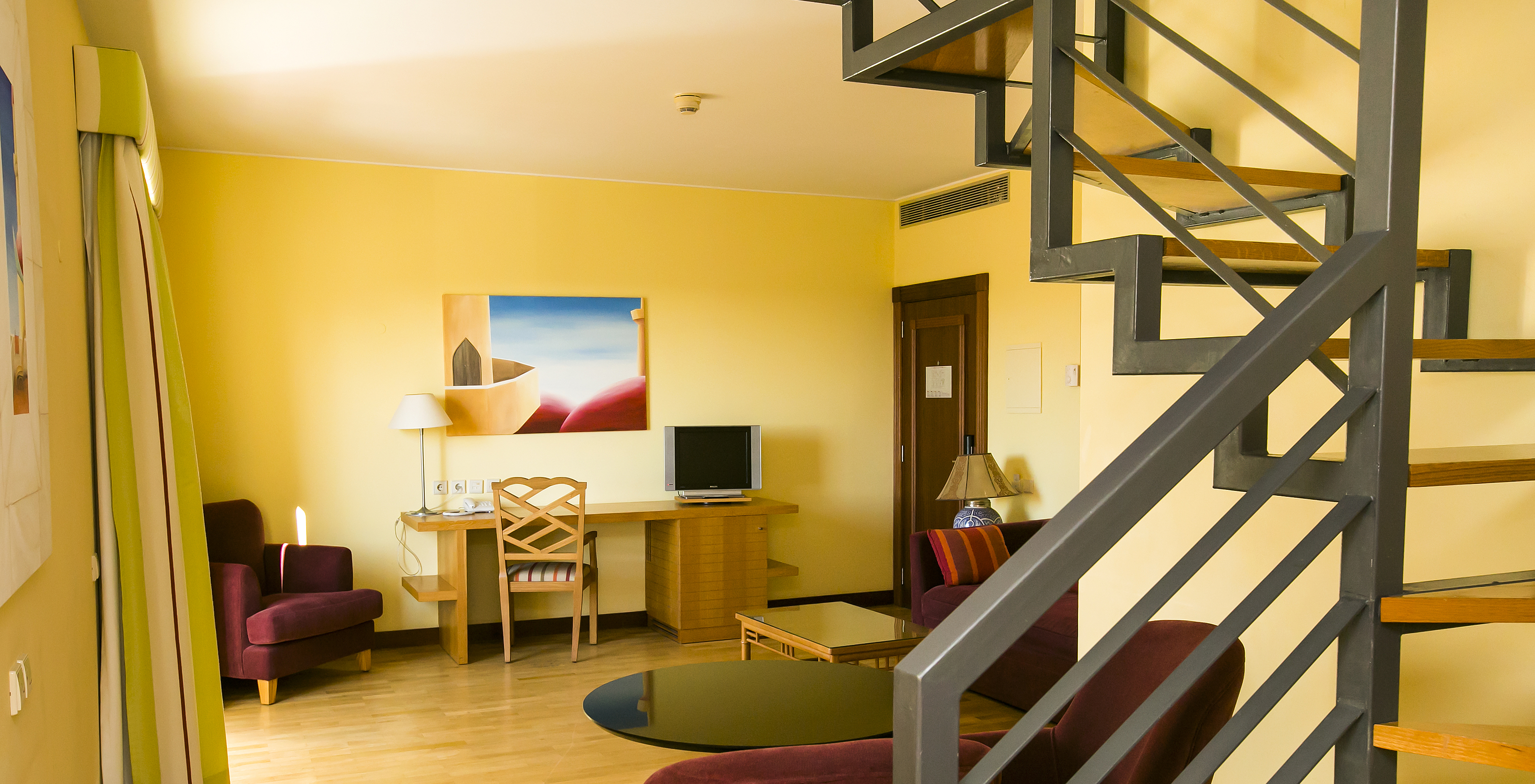 The Deluxe Mezzanine Suite of Pestana Sintra Golf has a room with sofa, armchairs, television, and a picture on the wall