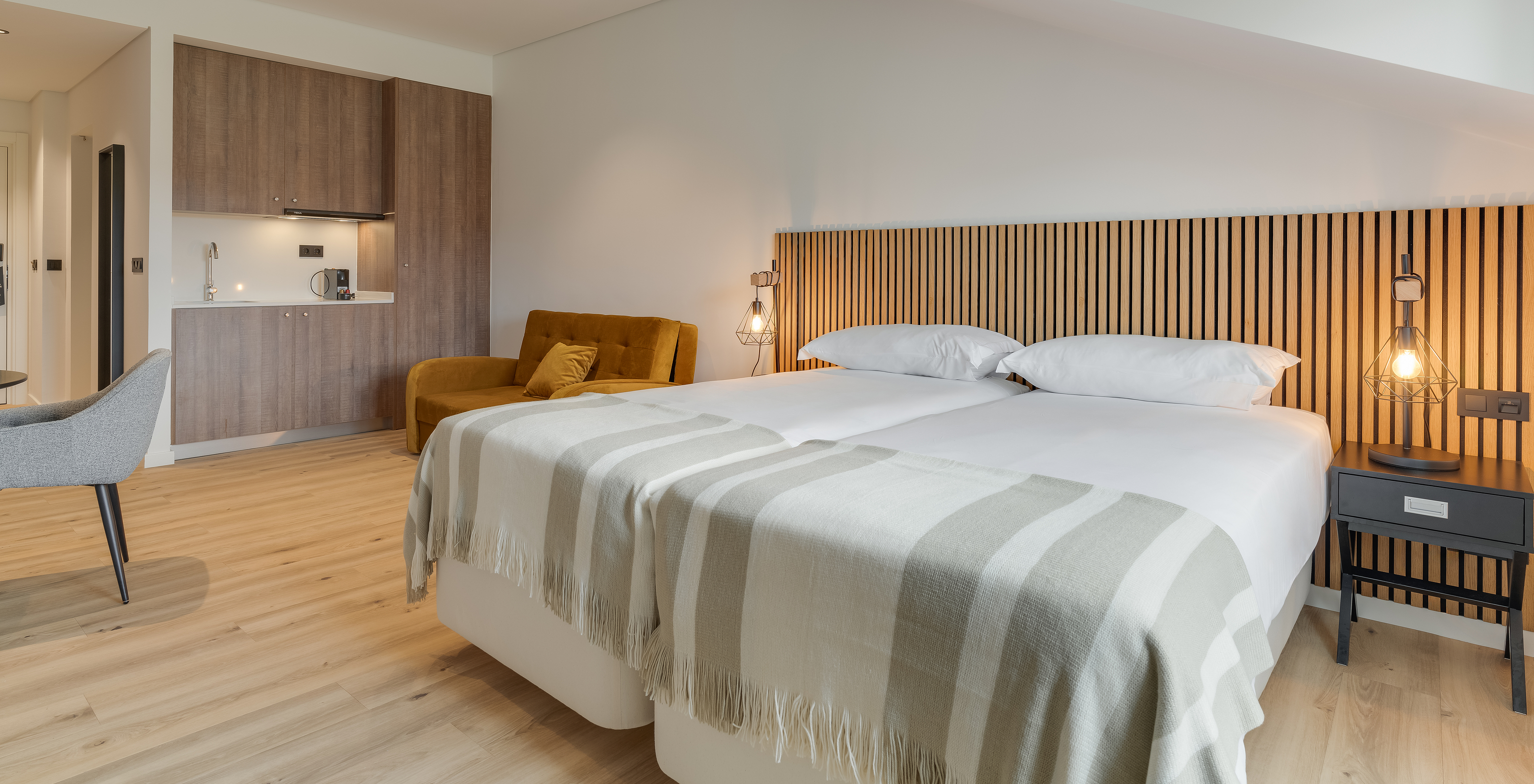 The Family - Clubhouse of Pestana Sintra Golf has two beds with wooden headboards, a sofa, and a kitchenette