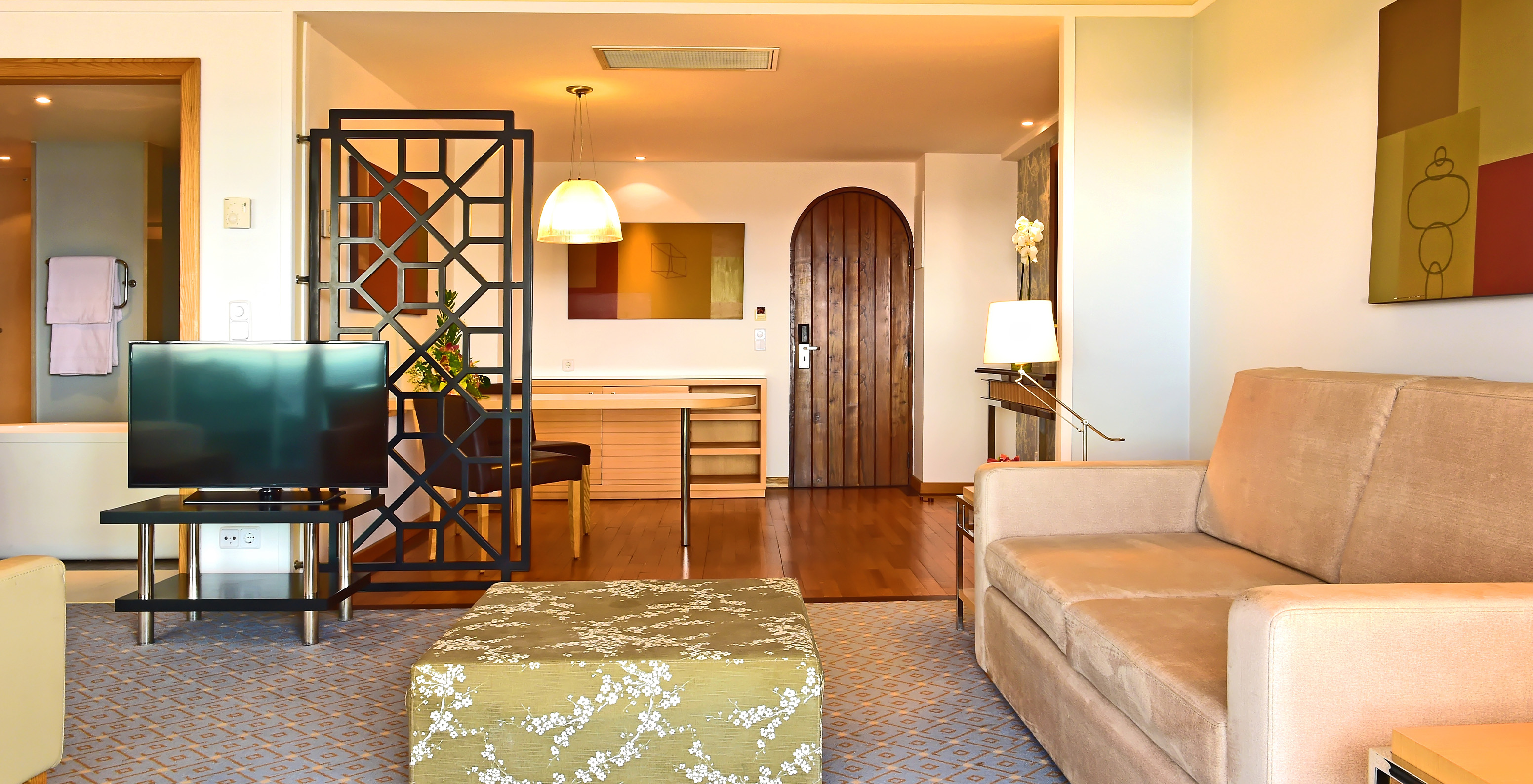 The Junior Suite at Pestana Carlton Madeira has a living room with a sofa, TV, and an entrance area