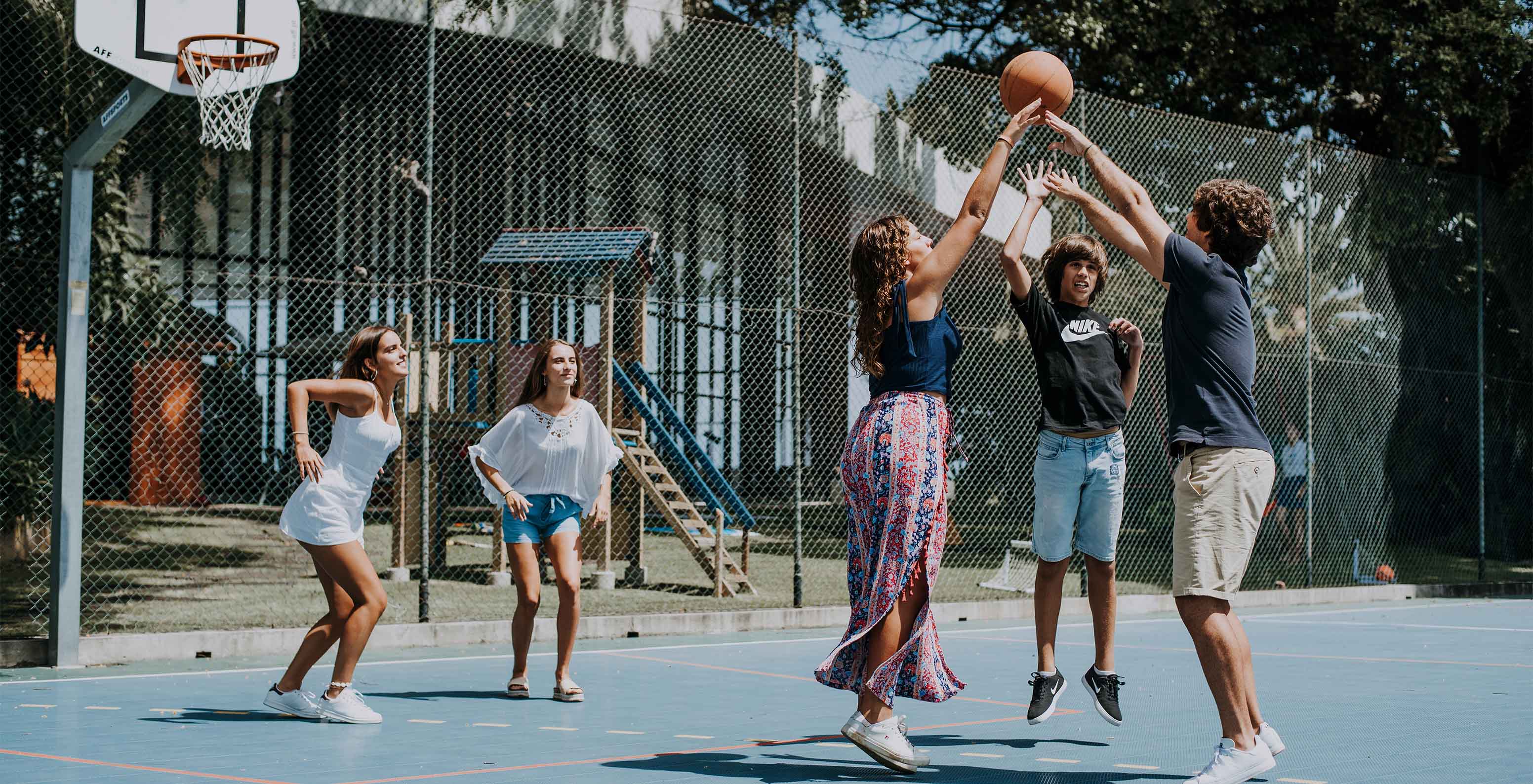 Five young people playing basketball at the kids club in the hotel in Funchal by the sea, with spa and pool