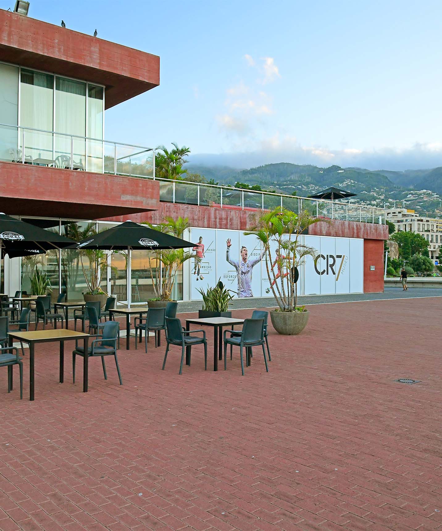 Patio of Corner restaurant with tables, chairs, and umbrellas outside the 4-star hotel in Funchal