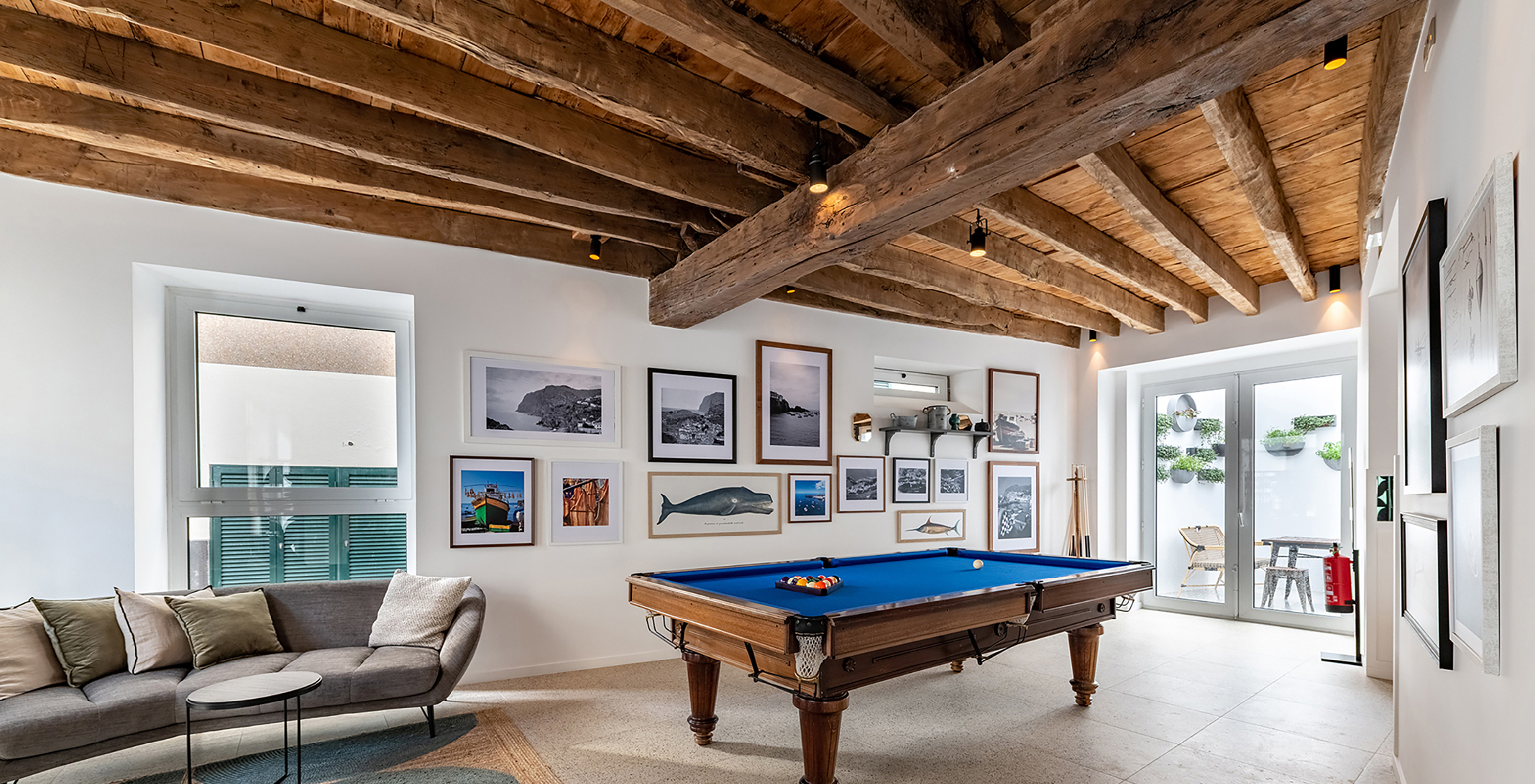 Blue billiard table of the boutique hotel in the historic center of Câmara de Lobos, with a sofa nearby and wooden ceiling