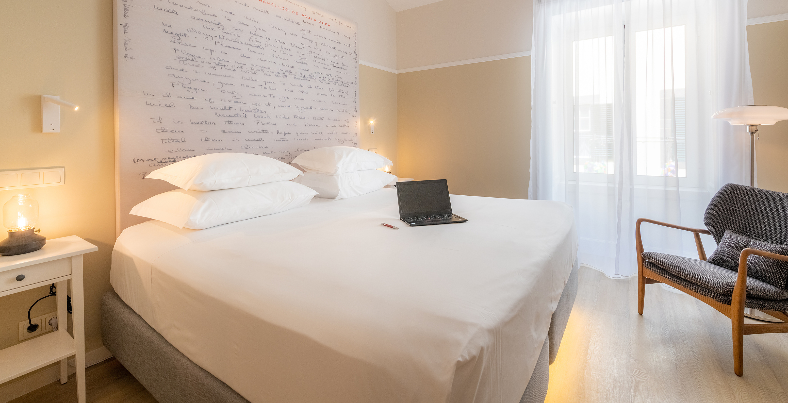 The Cozy room at Pestana Fisherman Village includes a double bed with a headboard with written phrases and an armchair