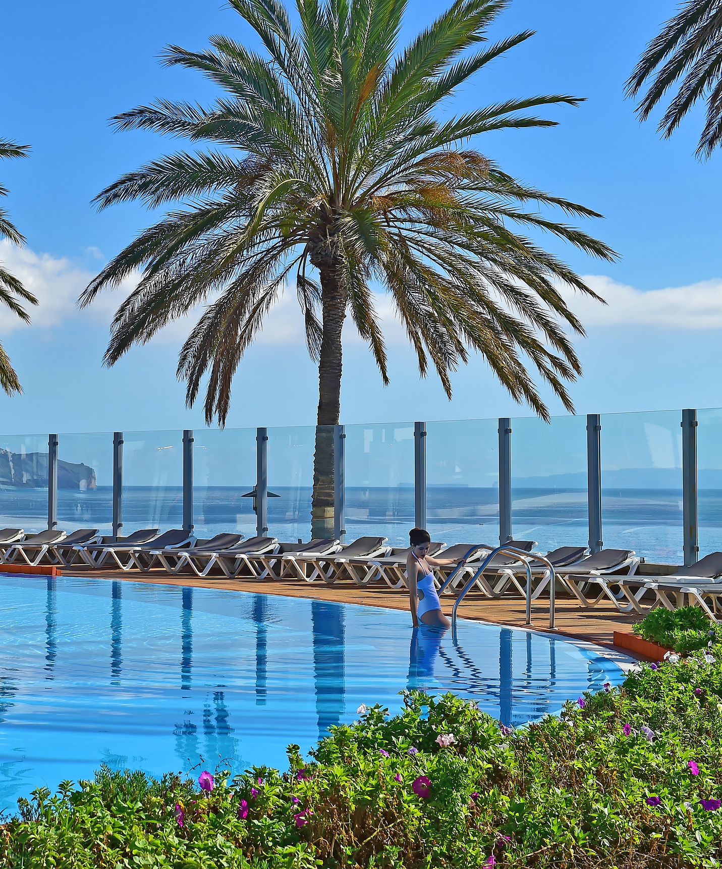 Pestana Grand, hotel with spa and pool, facing the sea, features an outdoor pool with sea views and palm trees around