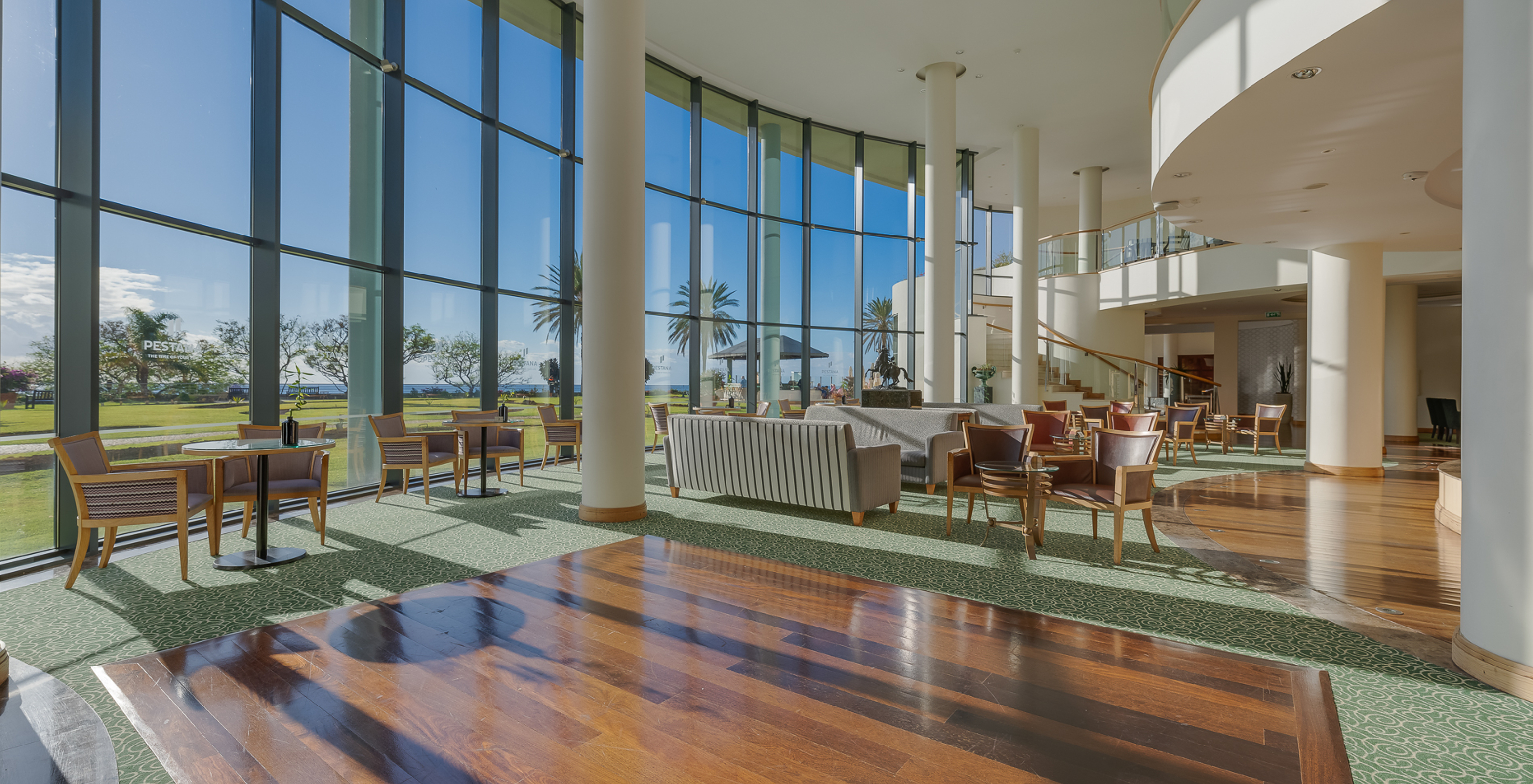 The Pestana Grand, a hotel with spa and pool, facing the sea, has an entrance hall with sofas, chairs, and tables