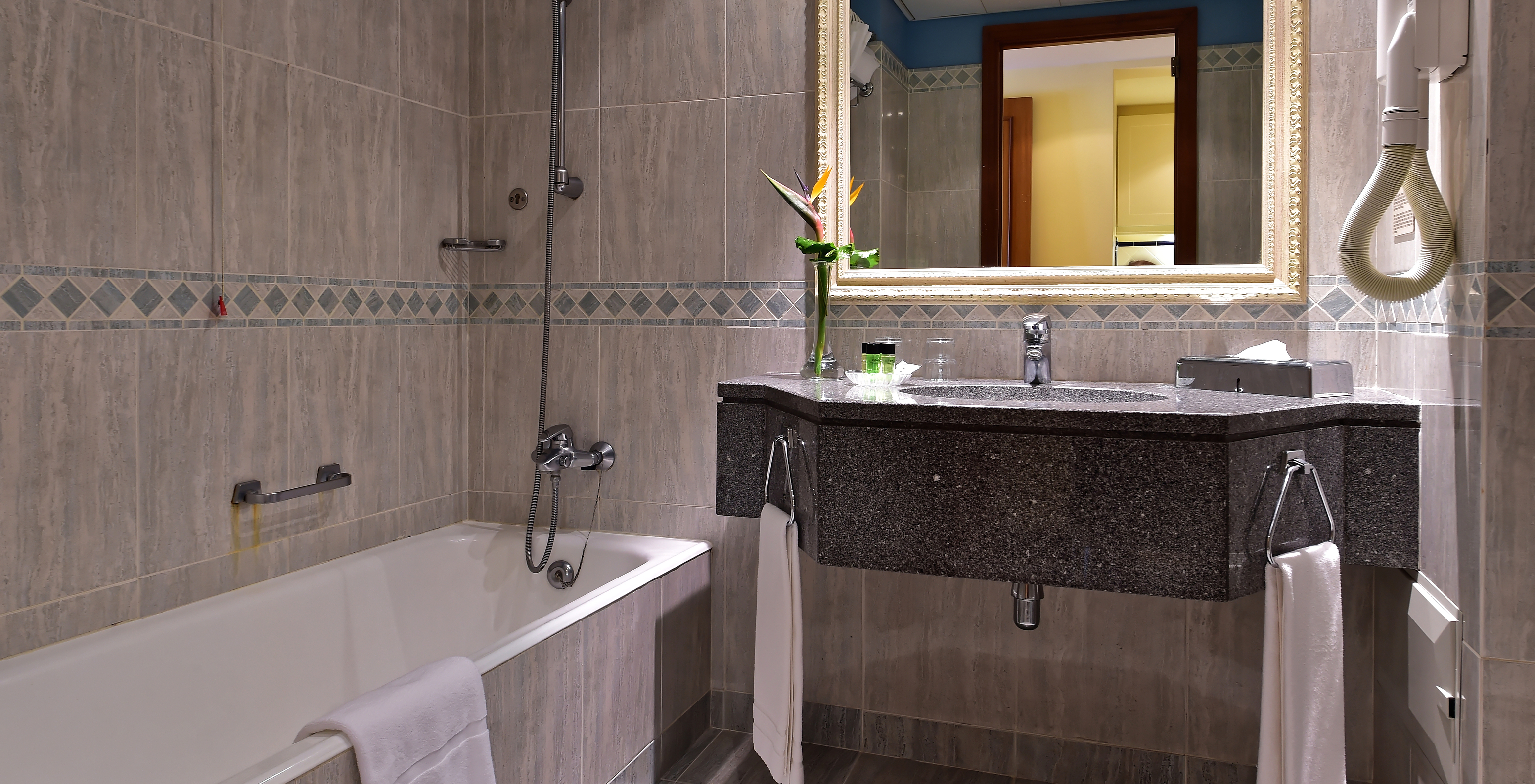 The Superior Room at Pestana Miramar has a bathroom with gray tiles, bathtub and a dark sink