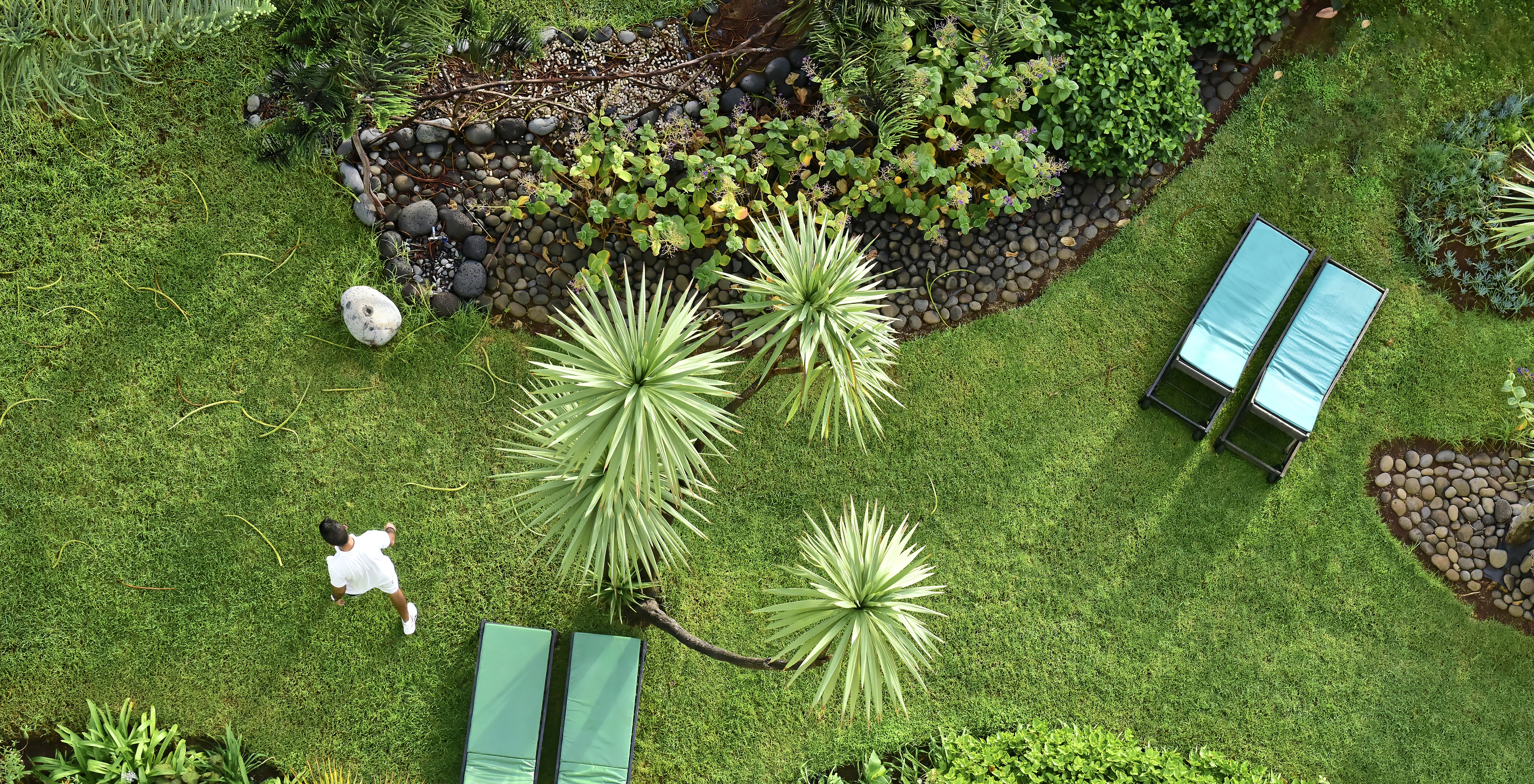 Aerial view of a garden with a person walking, at the all-inclusive hotel by the sea, with pool