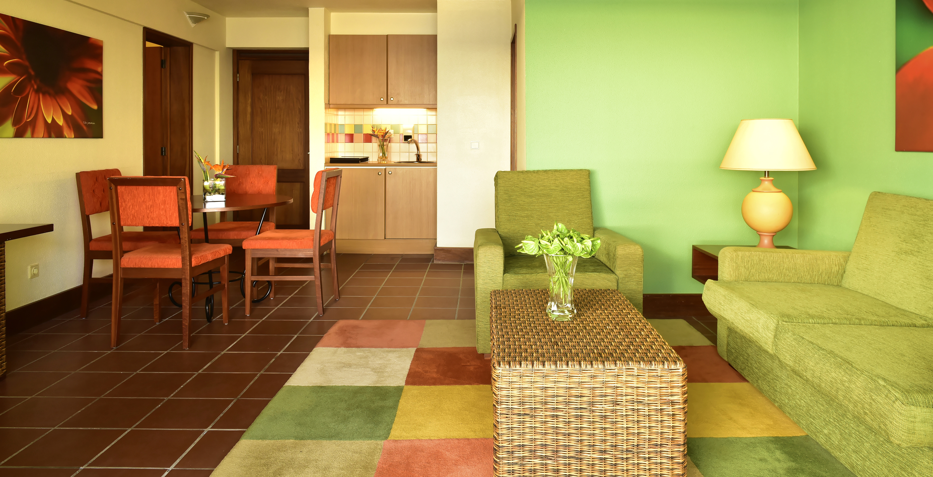 The Suite at Pestana Ocean Bay All Inclusive has a living room with green sofas, a dining table, and a kitchen