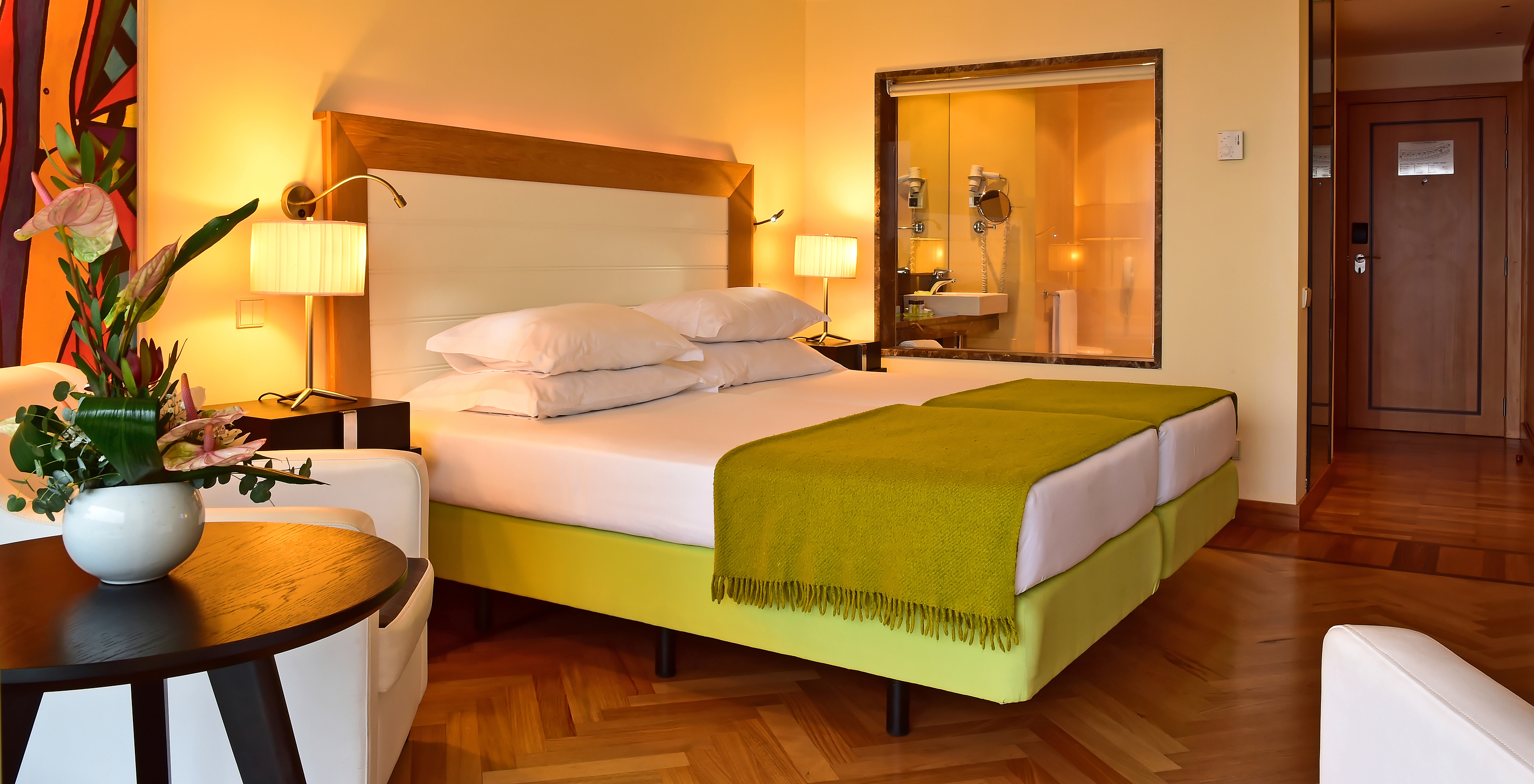 The Classic Pool View of Pestana Promenade has a bed with a green bedspread and a glass to the bathroom at the back