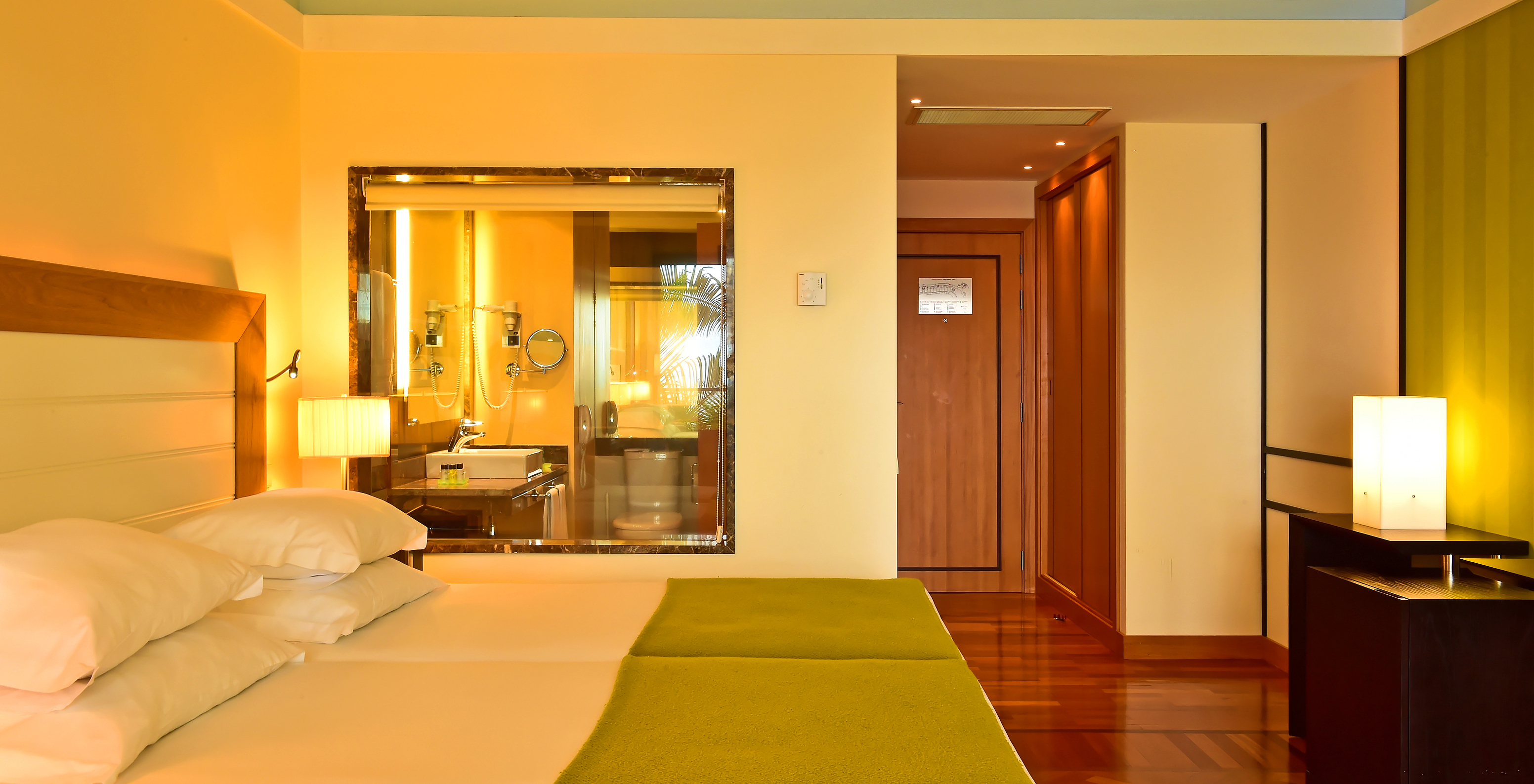 The Classic Sea View of Pestana Promenade has a bed with a green bedspread and a glass to the bathroom at the back