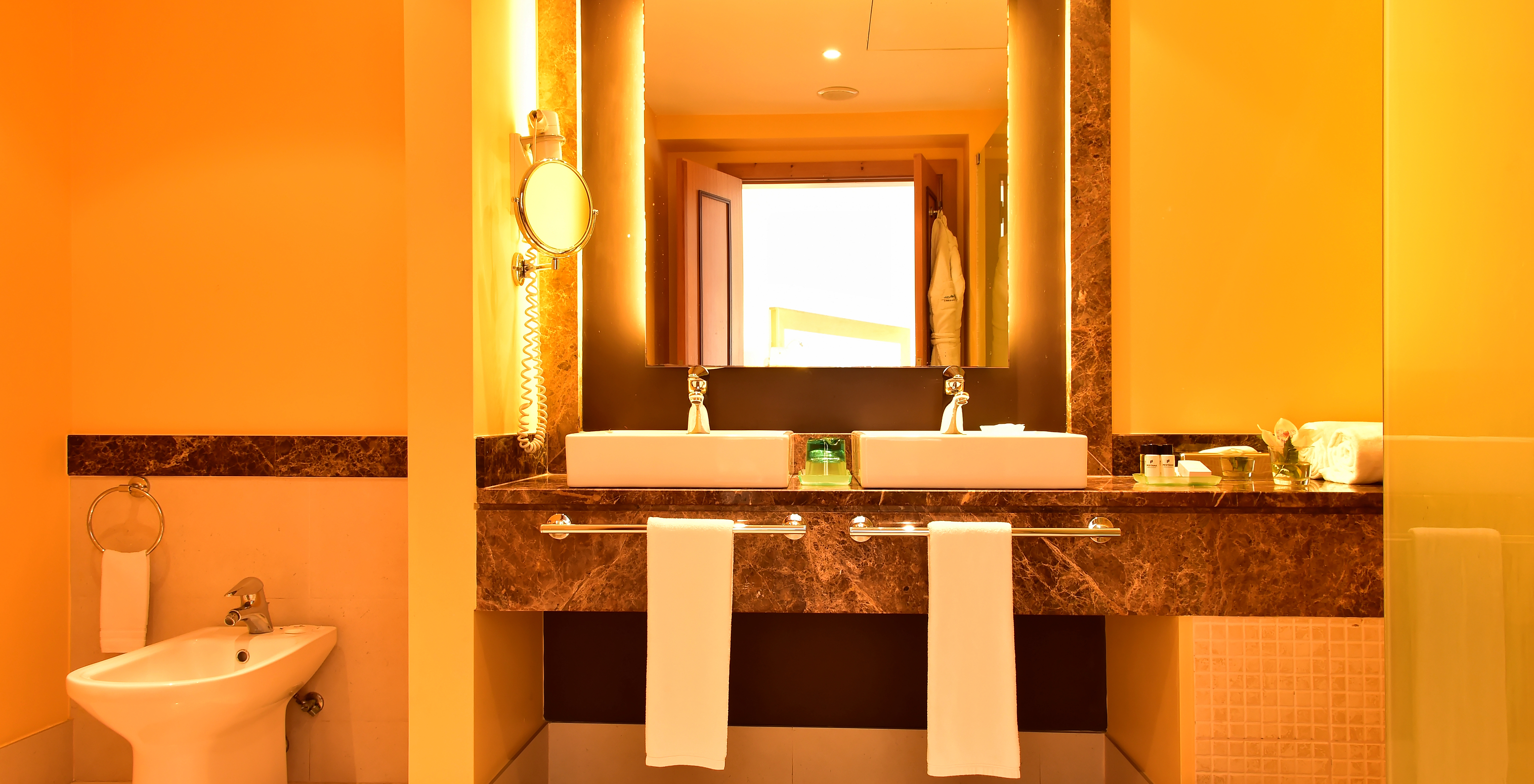 The Suite of Pestana Promenade has a bathroom with a brown framed mirror, two sinks, and a bidet