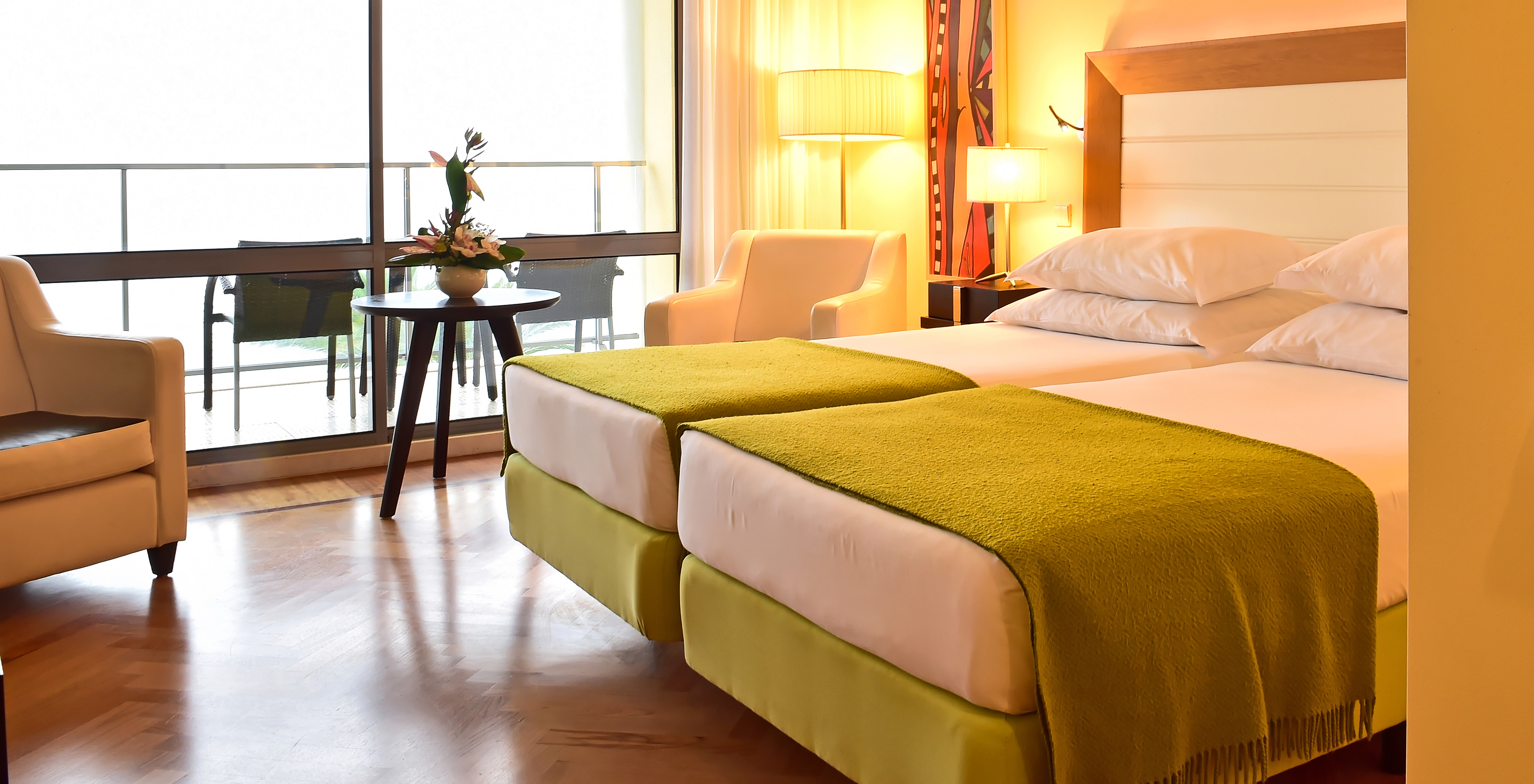 The Superior of Pestana Promenade has two beds with a green bedspread and a large window to the balcony