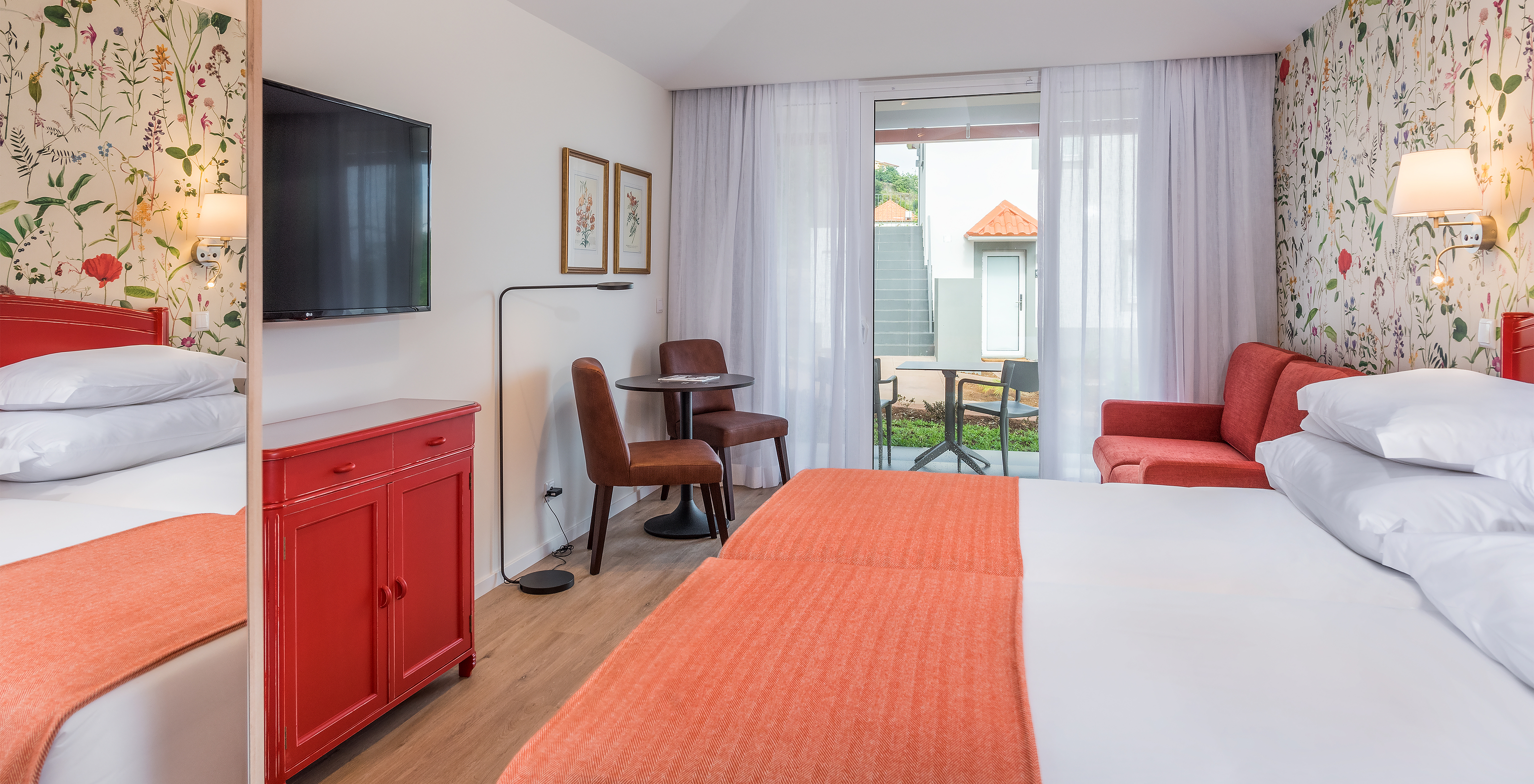 The Sea View Studio of Pestana Quinta do Arco has two joined beds, television, red sofa, and balcony with table and chairs