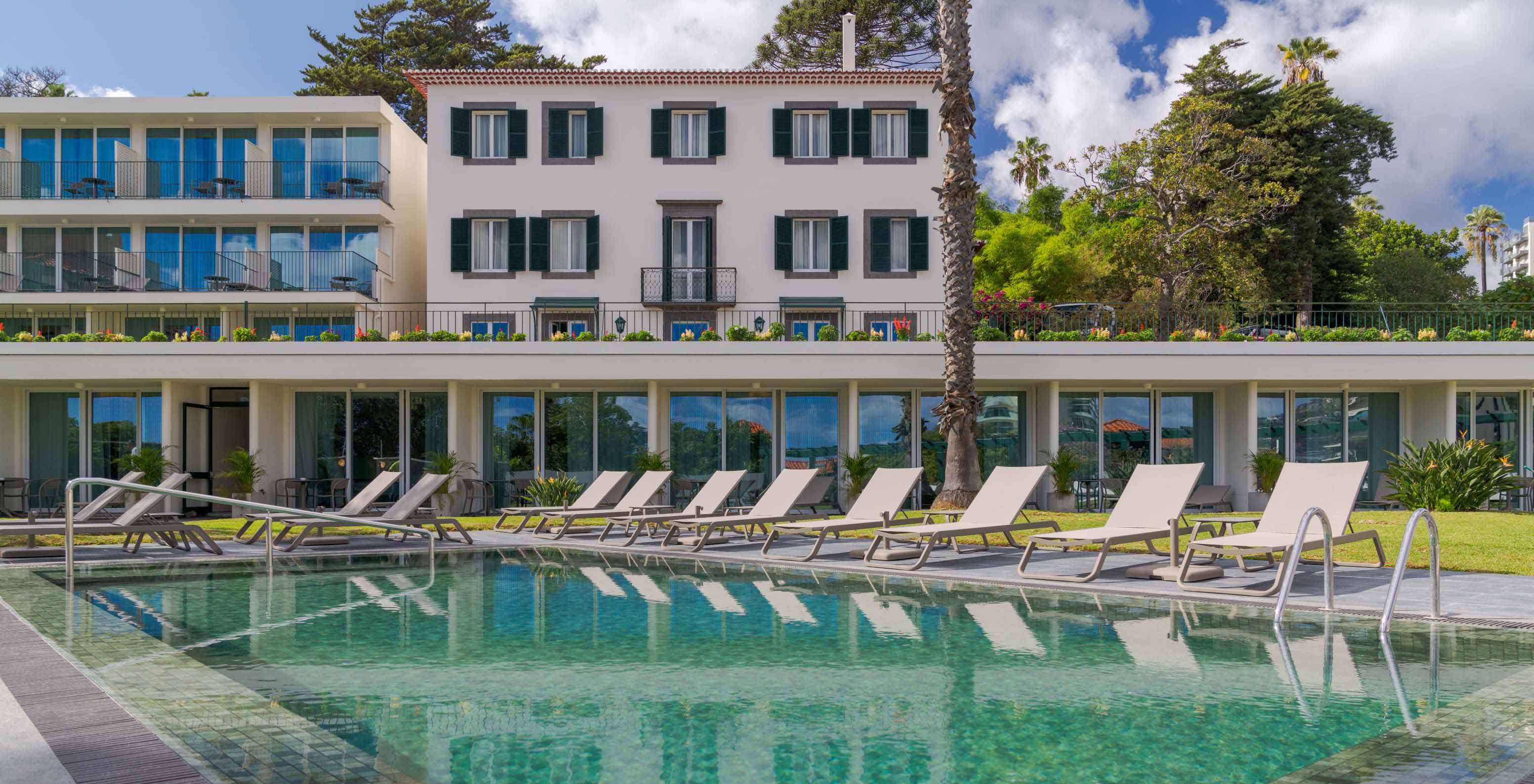 Vista da piscina exterior do Pestana Quinta Perestrello, um Hotel de Charme na Madeira, com o edifício atrás