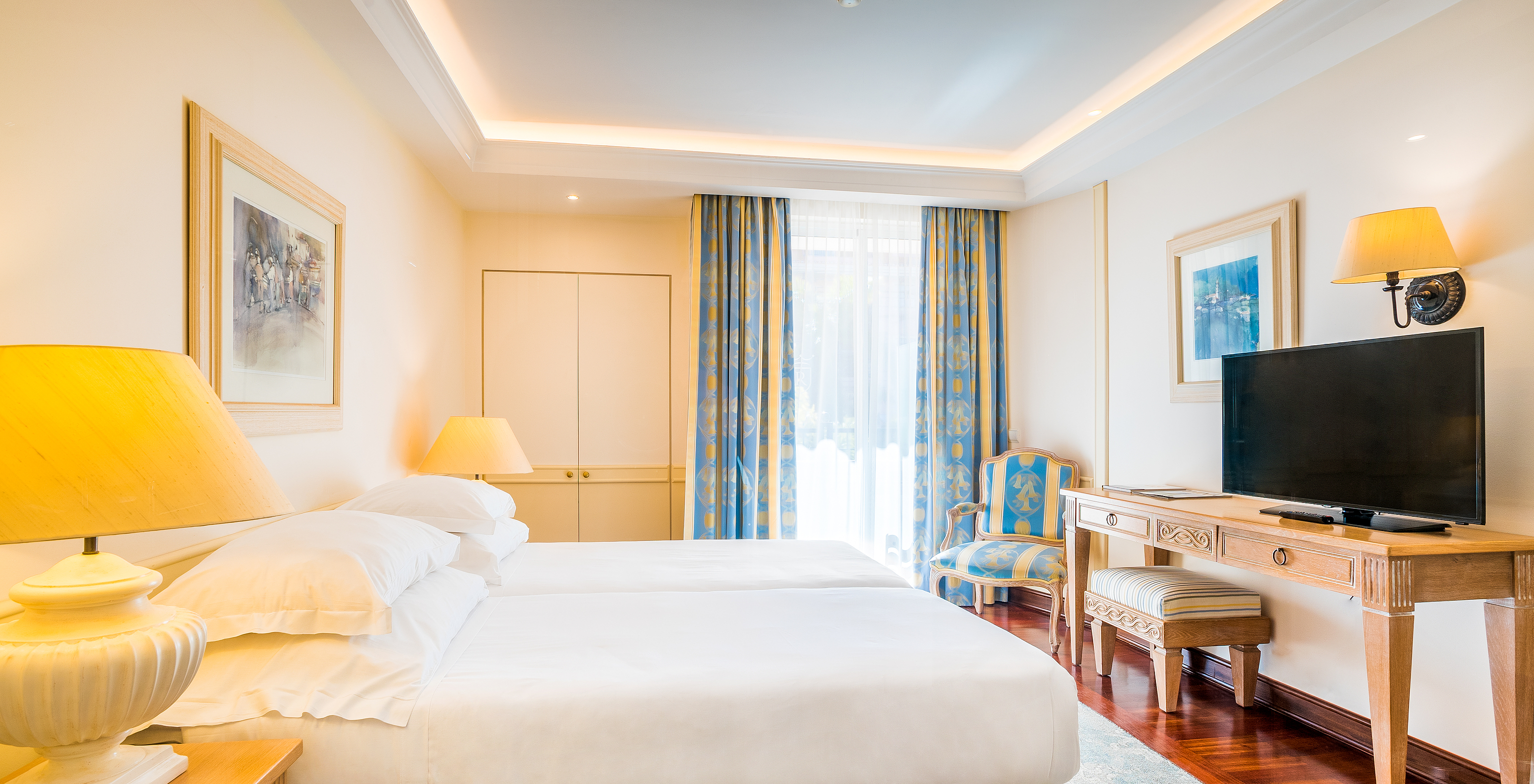 The Classic Room of Pestana Royal All Inclusive has two single beds, bedside table with lamp, and television