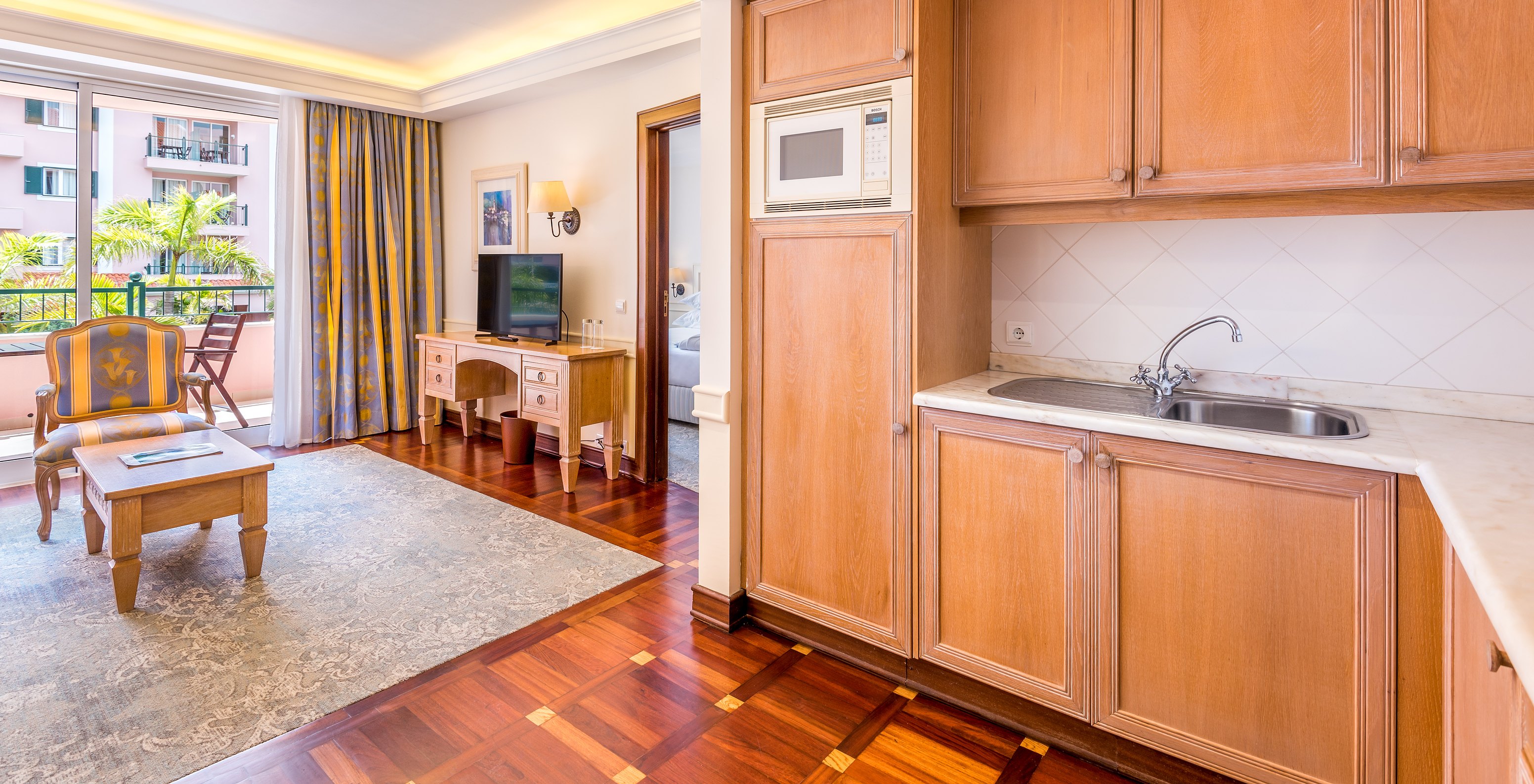 The Suite of Pestana Royal All Inclusive has a kitchen, and a living room with television, chairs, and a balcony