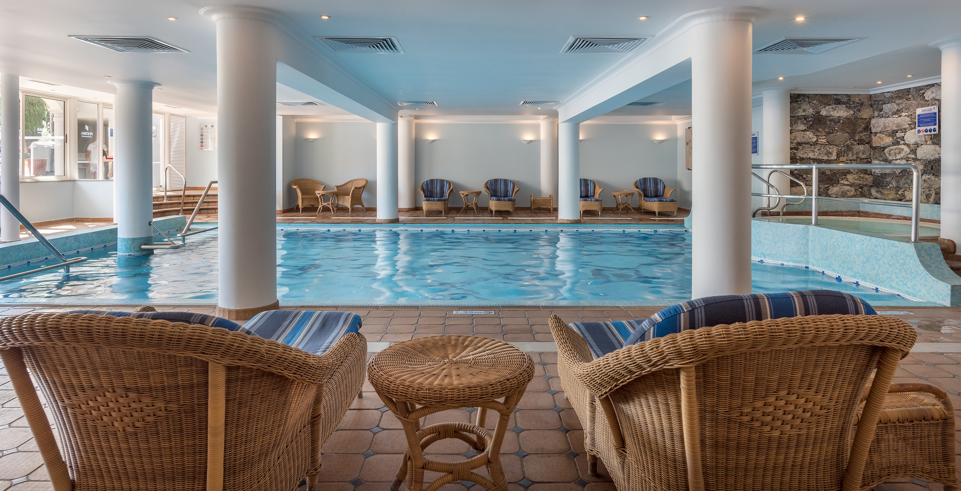 Heated indoor pool with bamboo chairs at Pestana Village, a Romantic Hotel in Funchal, Madeira