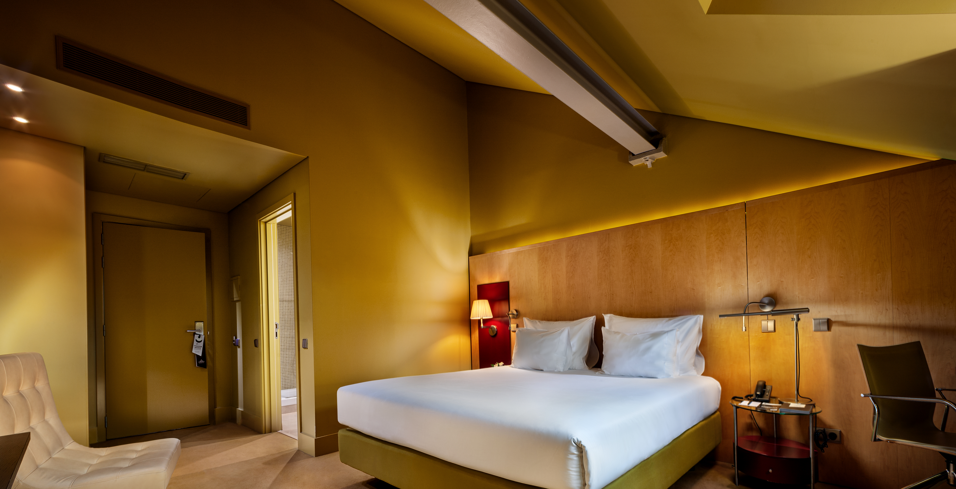 The Classic Attic of Pestana Palácio do Freixo has a room in toasted yellow with a double bed and an armchair