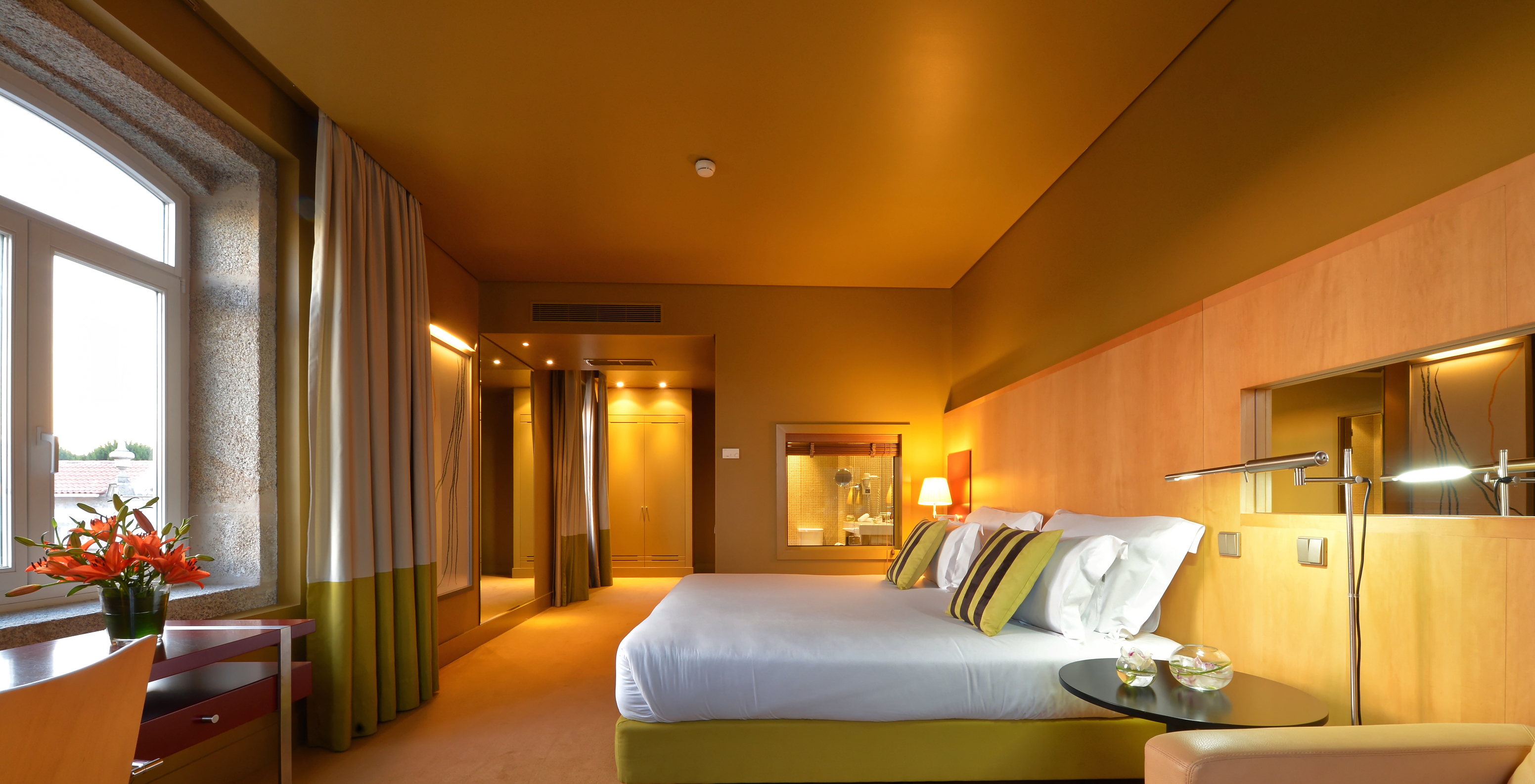 The Deluxe Grand View of Pestana Palácio do Freixo has a spacious room with a double bed, a mirror and a stone window