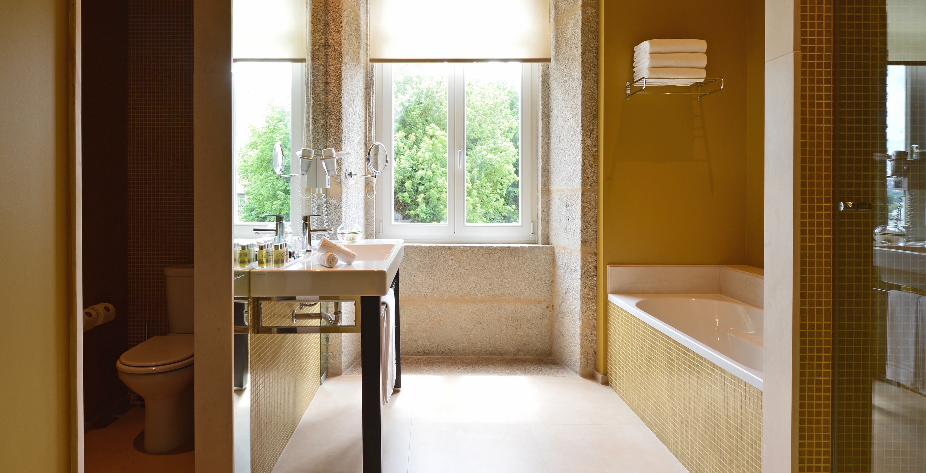 The Nasoni Suite of Pestana Palácio do Freixo has a bathroom with a bathtub, sink and window with a stone sill