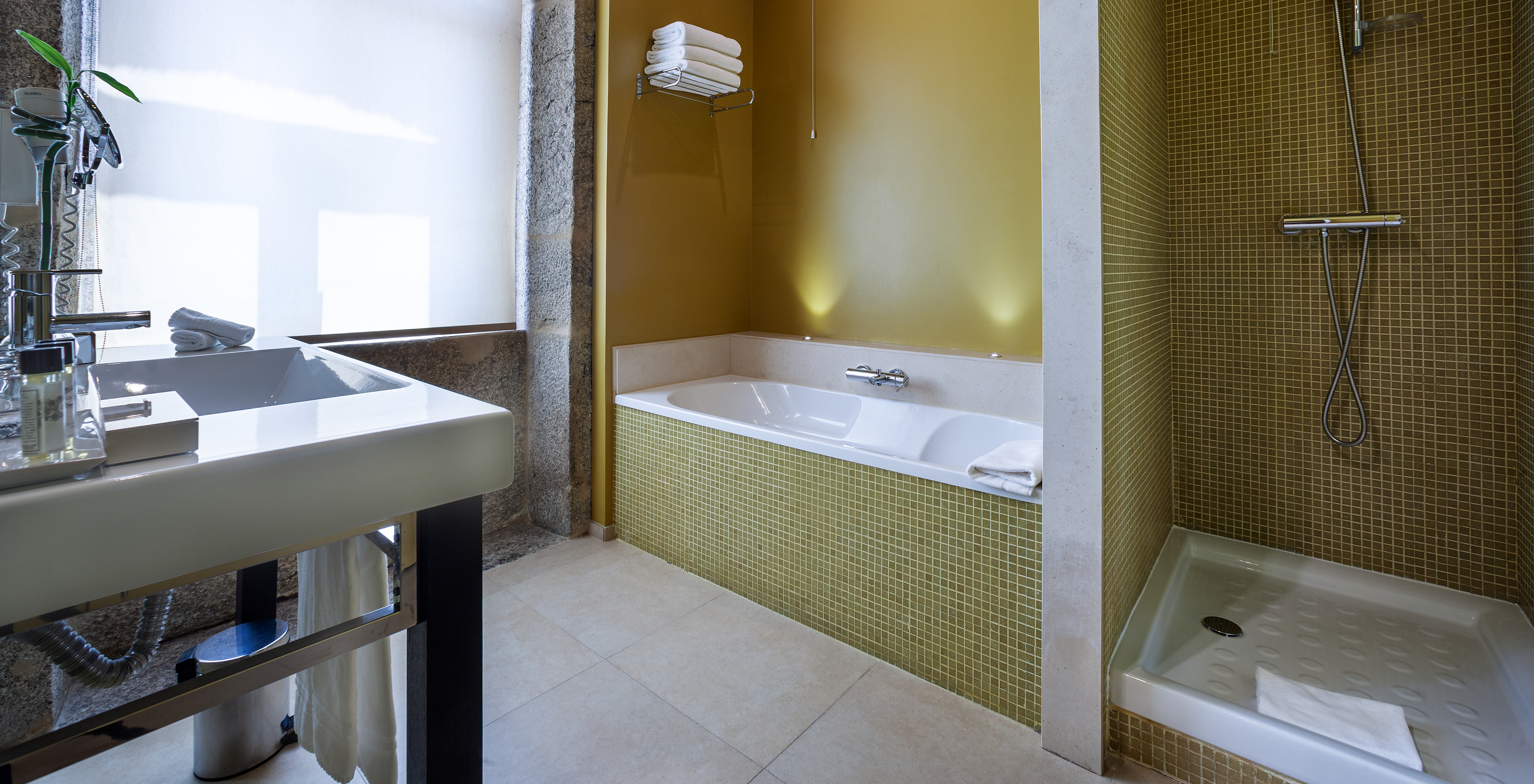 The Standard Suite of Pestana Palácio do Freixo has a bathroom with a bathtub, a shower and a large window