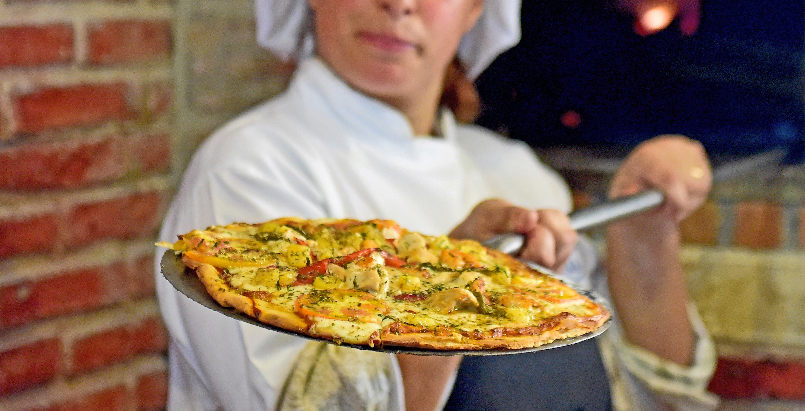 The Le Baron restaurant at the 4-Star Hotel in São Tomé has a chef making pizza with cheese and mushrooms