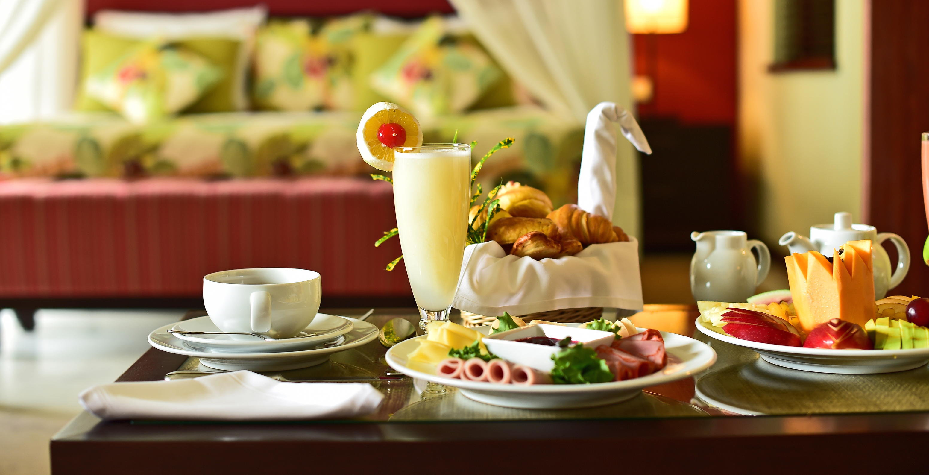 Meal served in the room with a variety of pastries, cold cuts, fruits, a cup of coffee, and juice