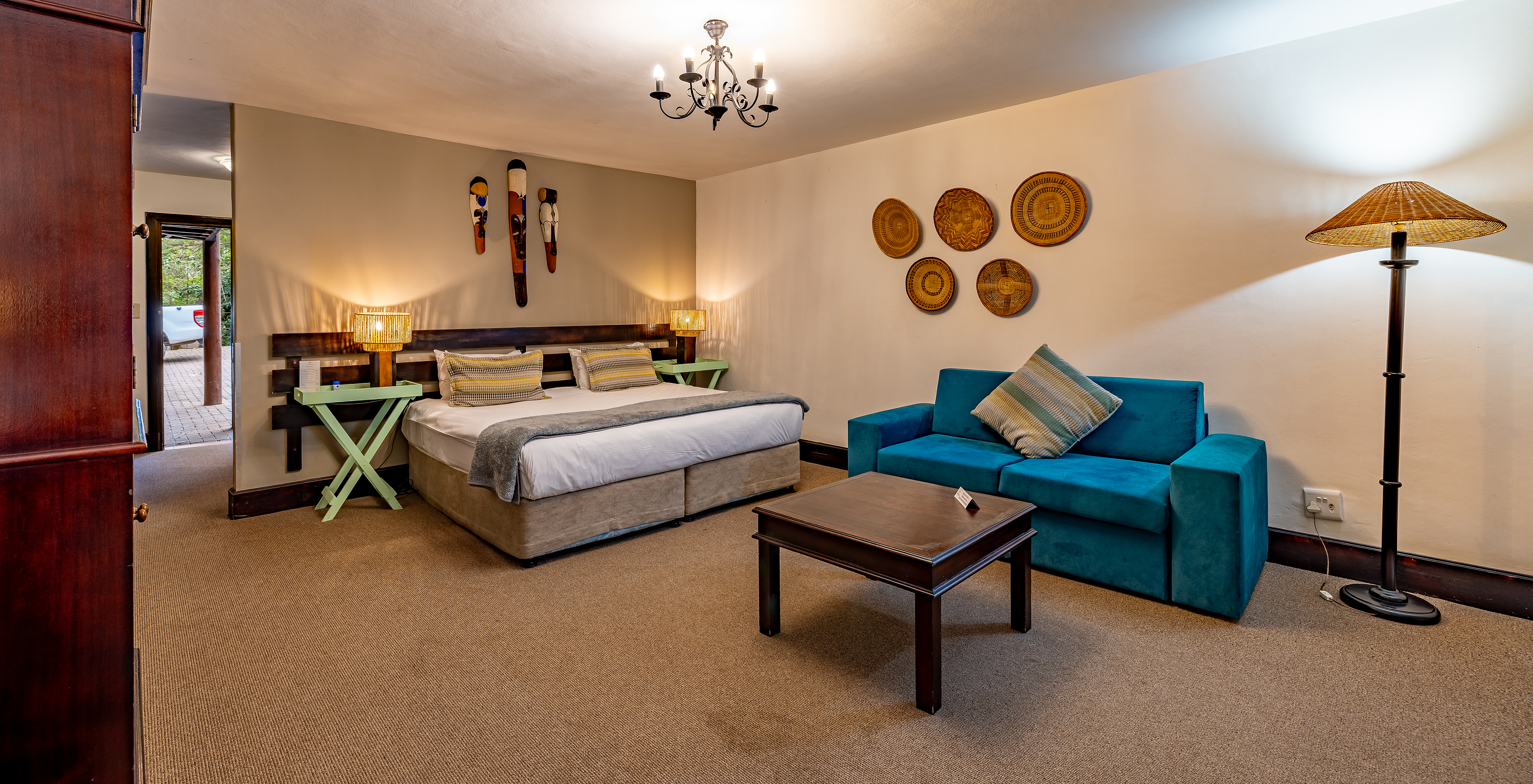 The Premium Room at Pestana Kruger Lodge has a double bed, a blue sofa and typical African decor