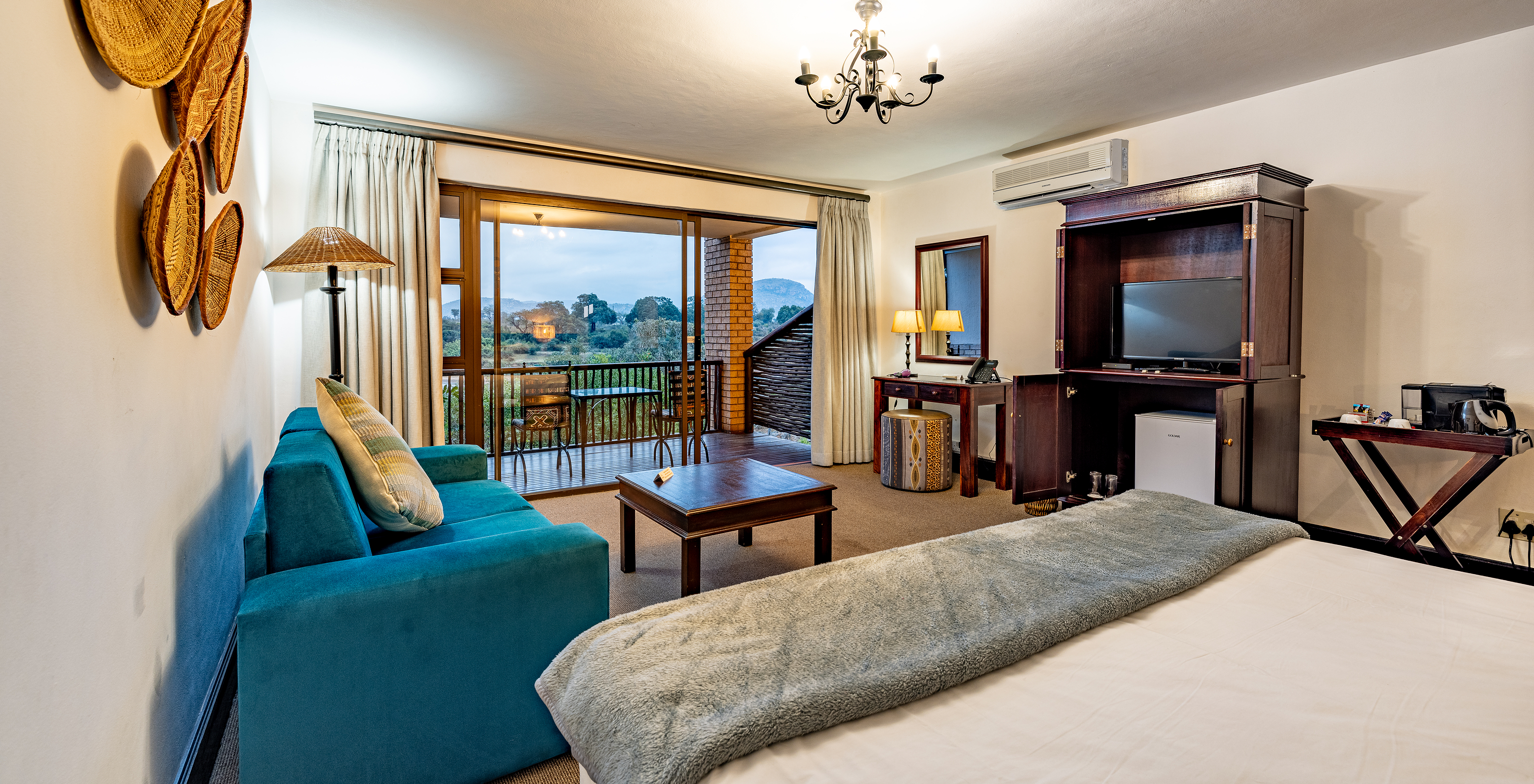 The Premium Room at Pestana Kruger Lodge has a seating area with sofa, TV and typical African decor