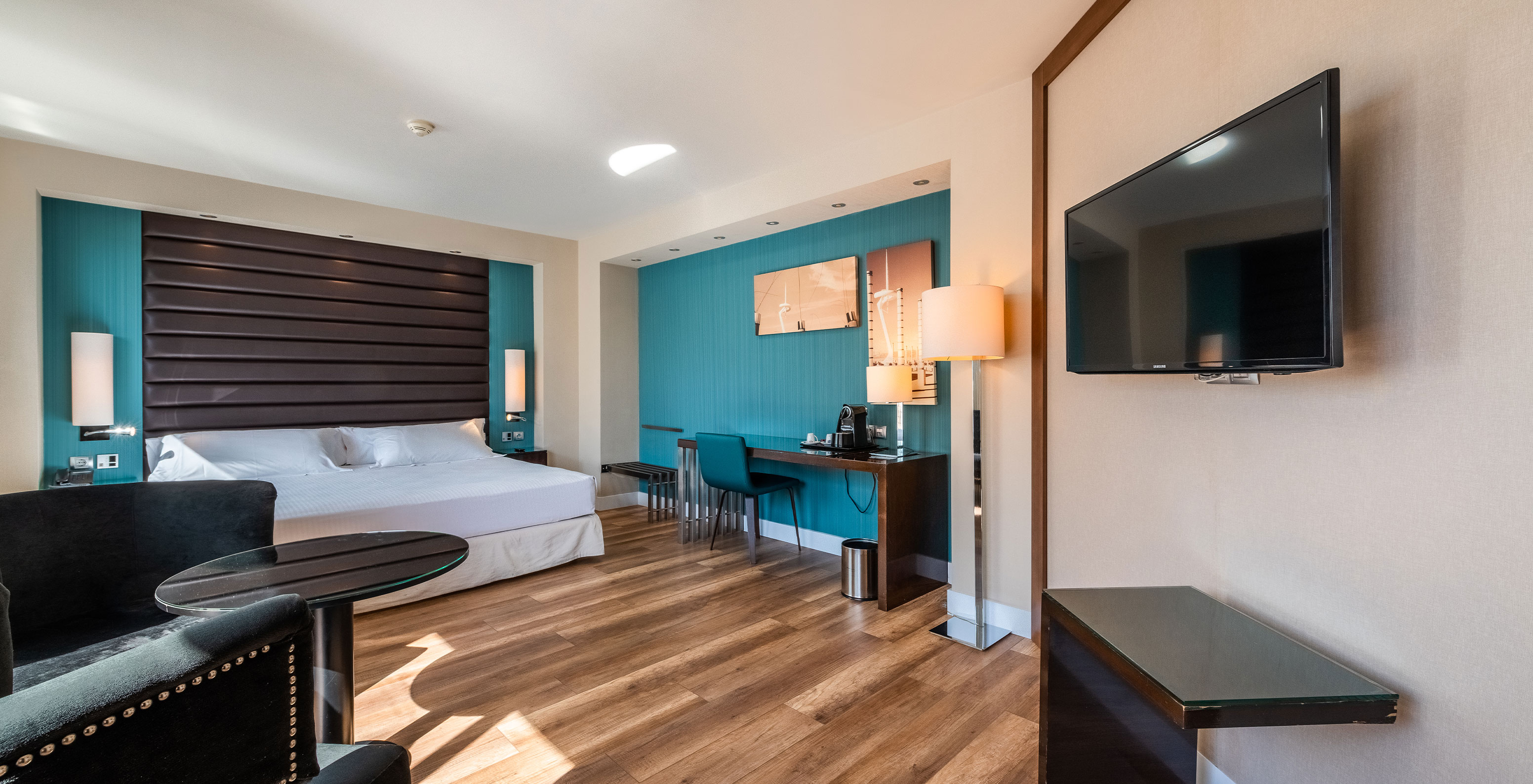 Junior Suite at Pestana Arena Barcelona has a spacious room with a TV in front of the sofa and a double bed