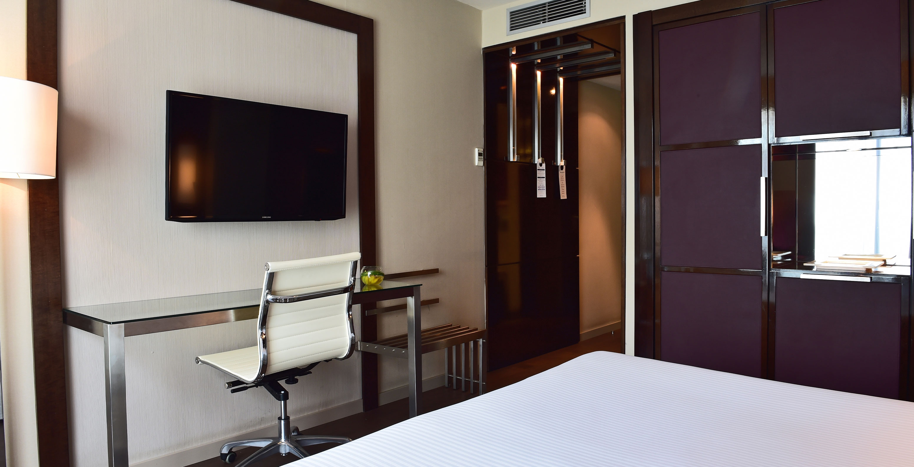 Premium King room at Pestana Arena Barcelona has a TV at the foot of the bed and a purple wardrobe for storage