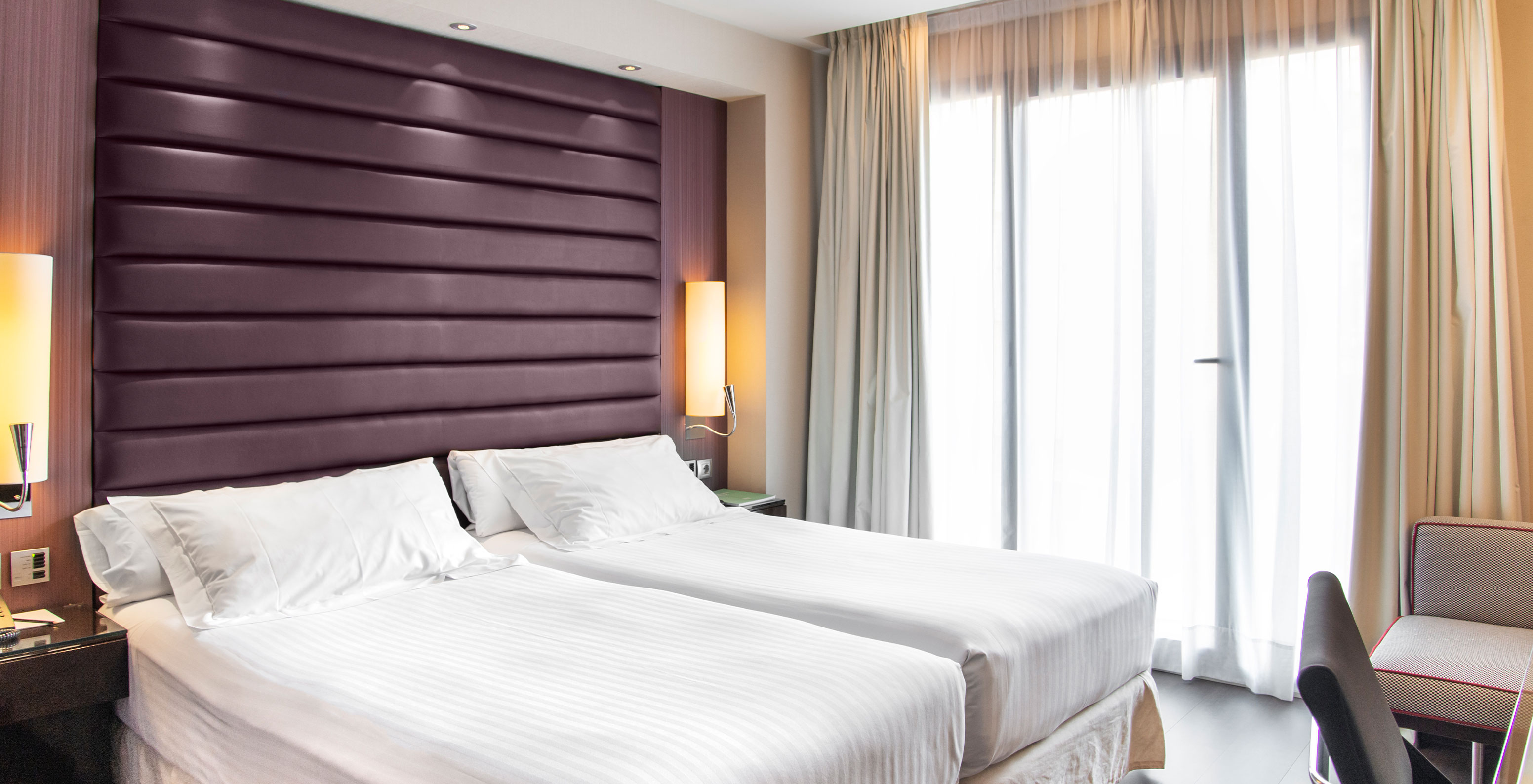 Standard Twin room at Pestana Arena Barcelona has two single beds with bedside table, an armchair and a window