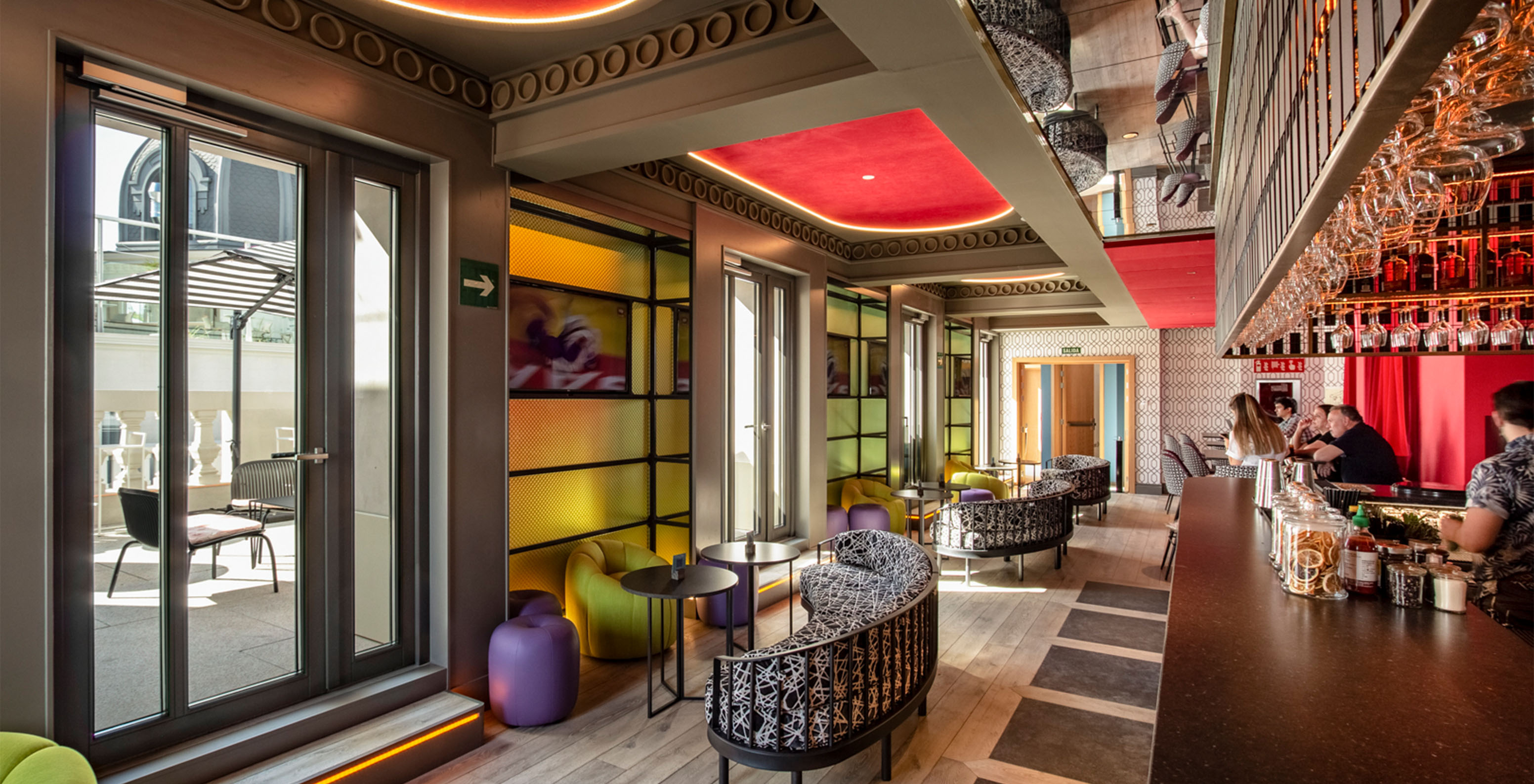 The Sports Bar at the hotel in central Madrid, Spain, has a colorful space with high stools, sofas, and poufs